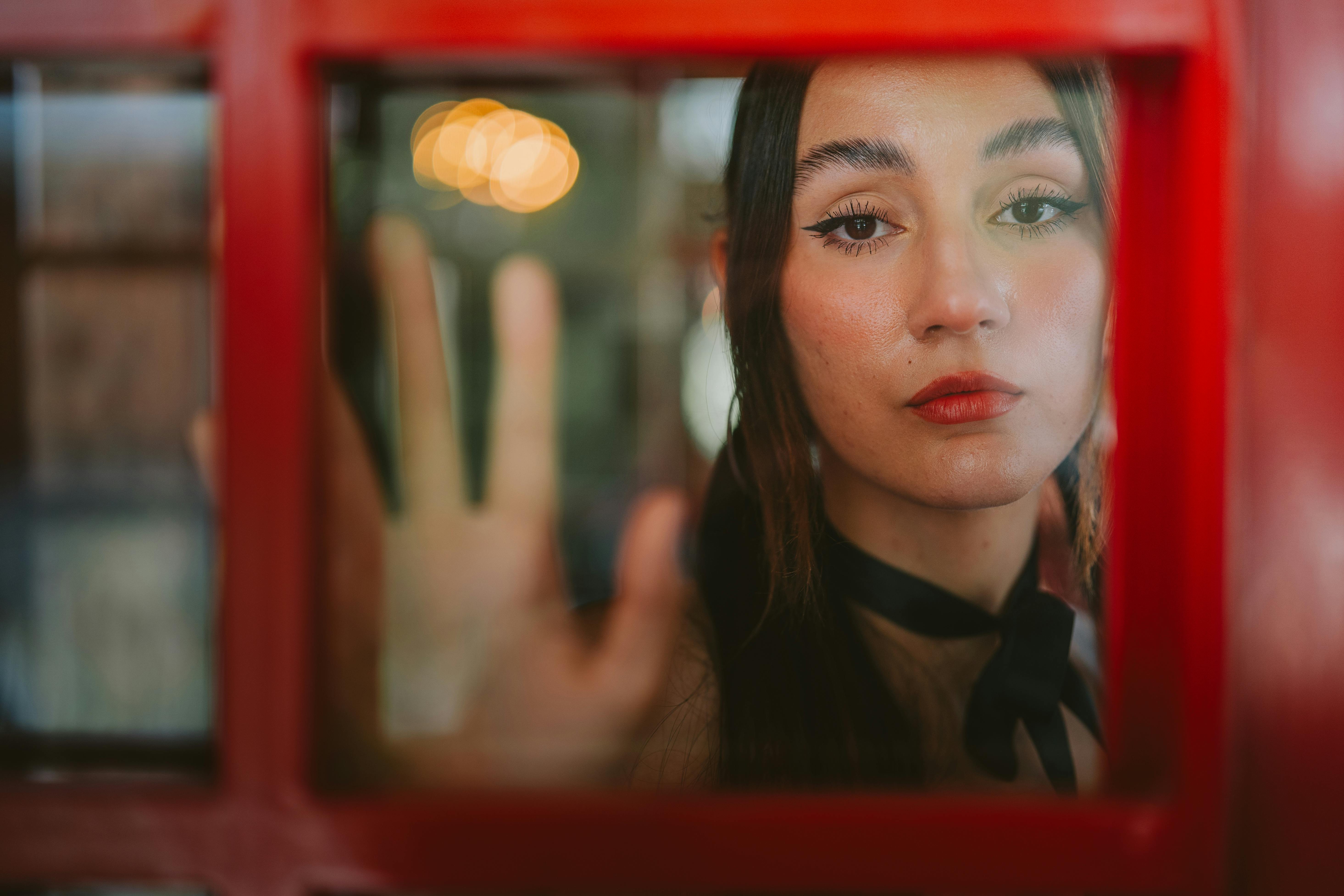 a woman looking out of a red telephone booth