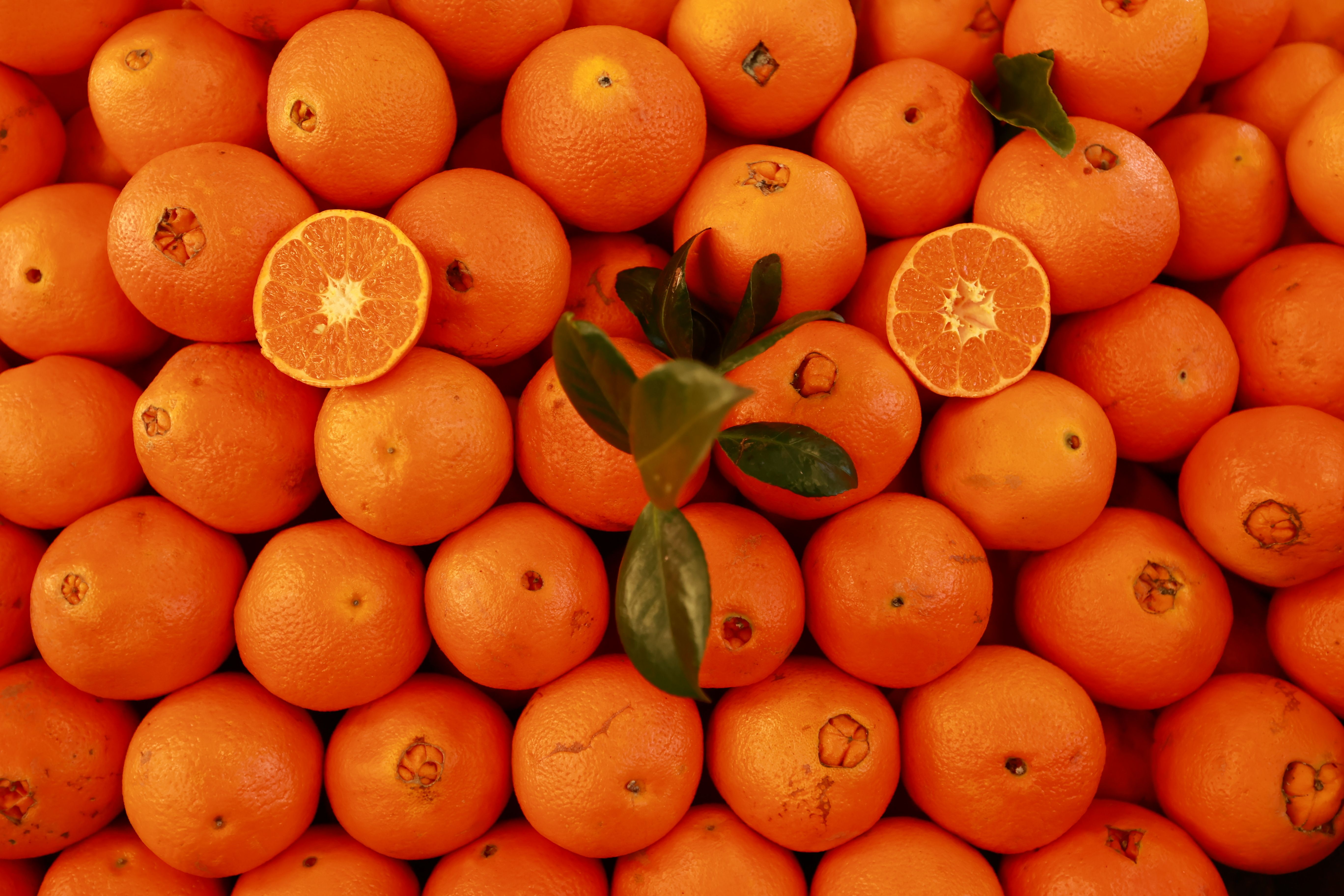 Vibrant pile of fresh tangerines and leafy greens showcasing natural bounty.