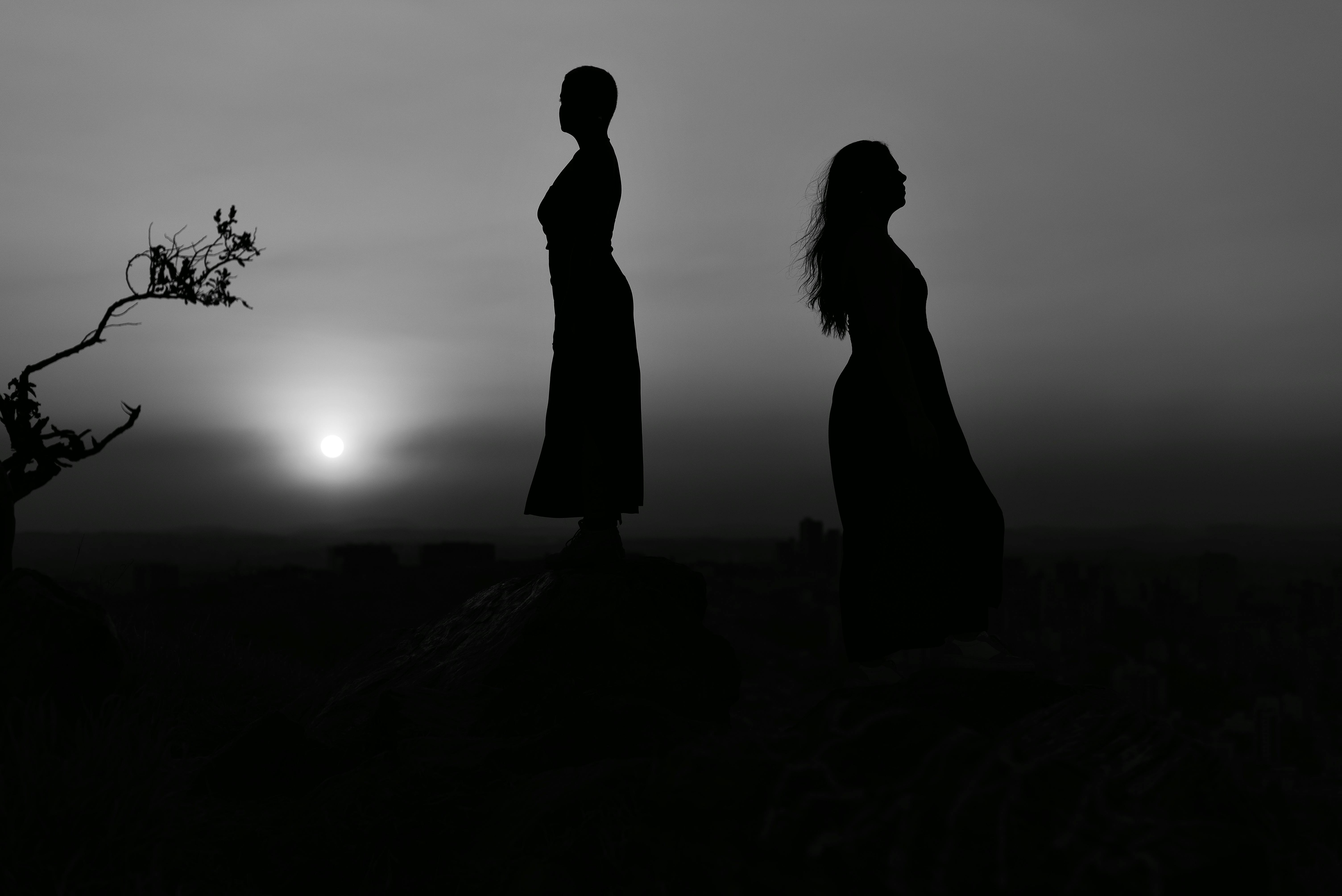 Silhouette of two women standing on rocks during sunset in Belo Horizonte, Brazil.