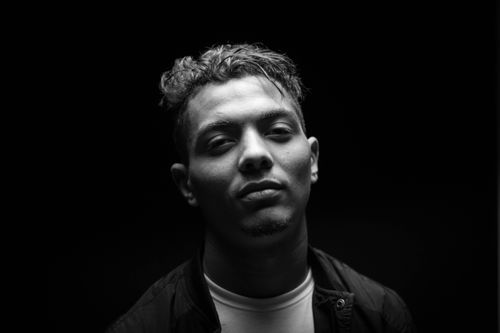 Free Black and white portrait of a young man with dramatic lighting, conveying a moody atmosphere. Stock Photo
