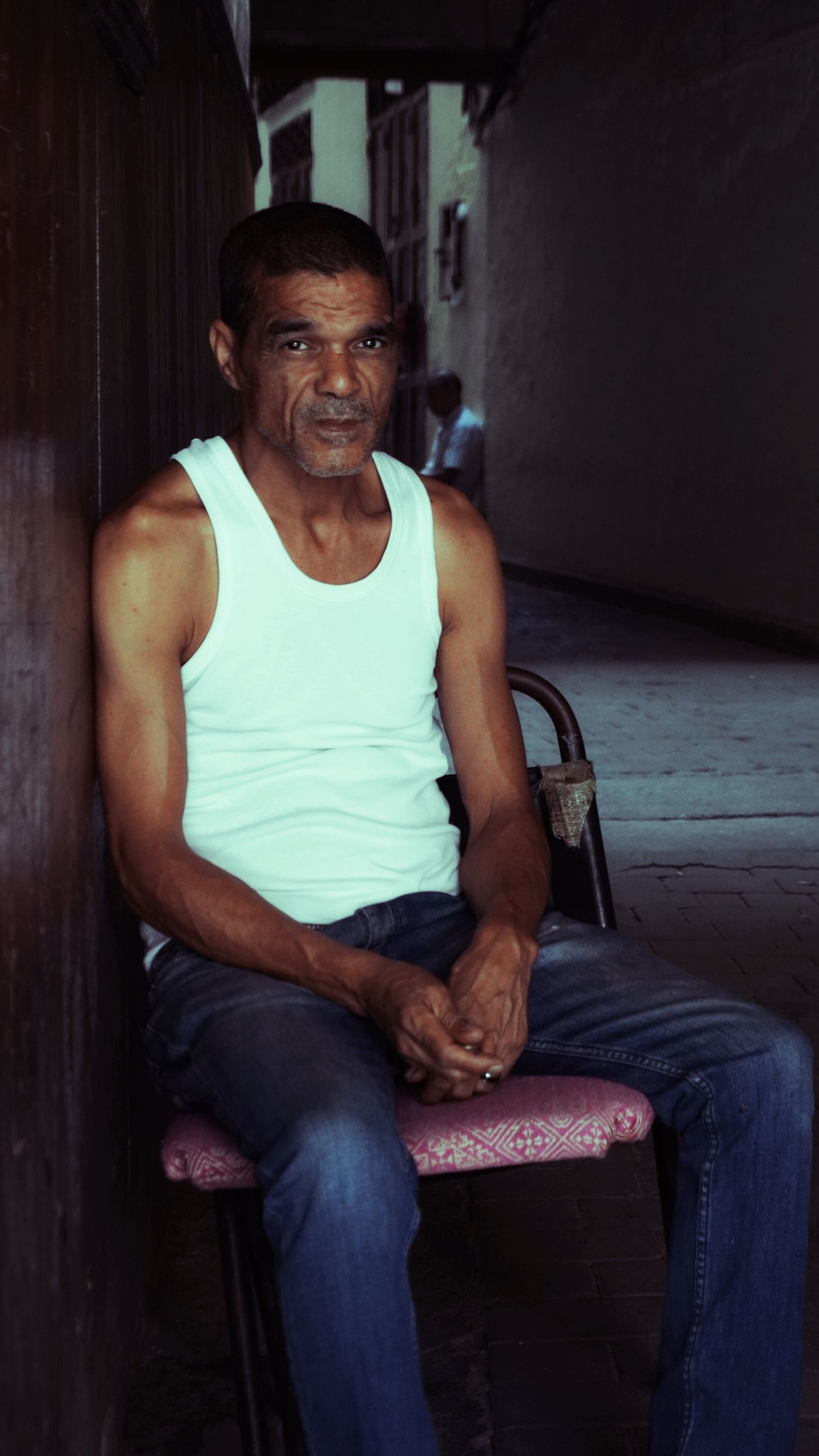 Fotomural Retrato de un hombre relajado sentado en un callejón, capturando un momento espontáneo.