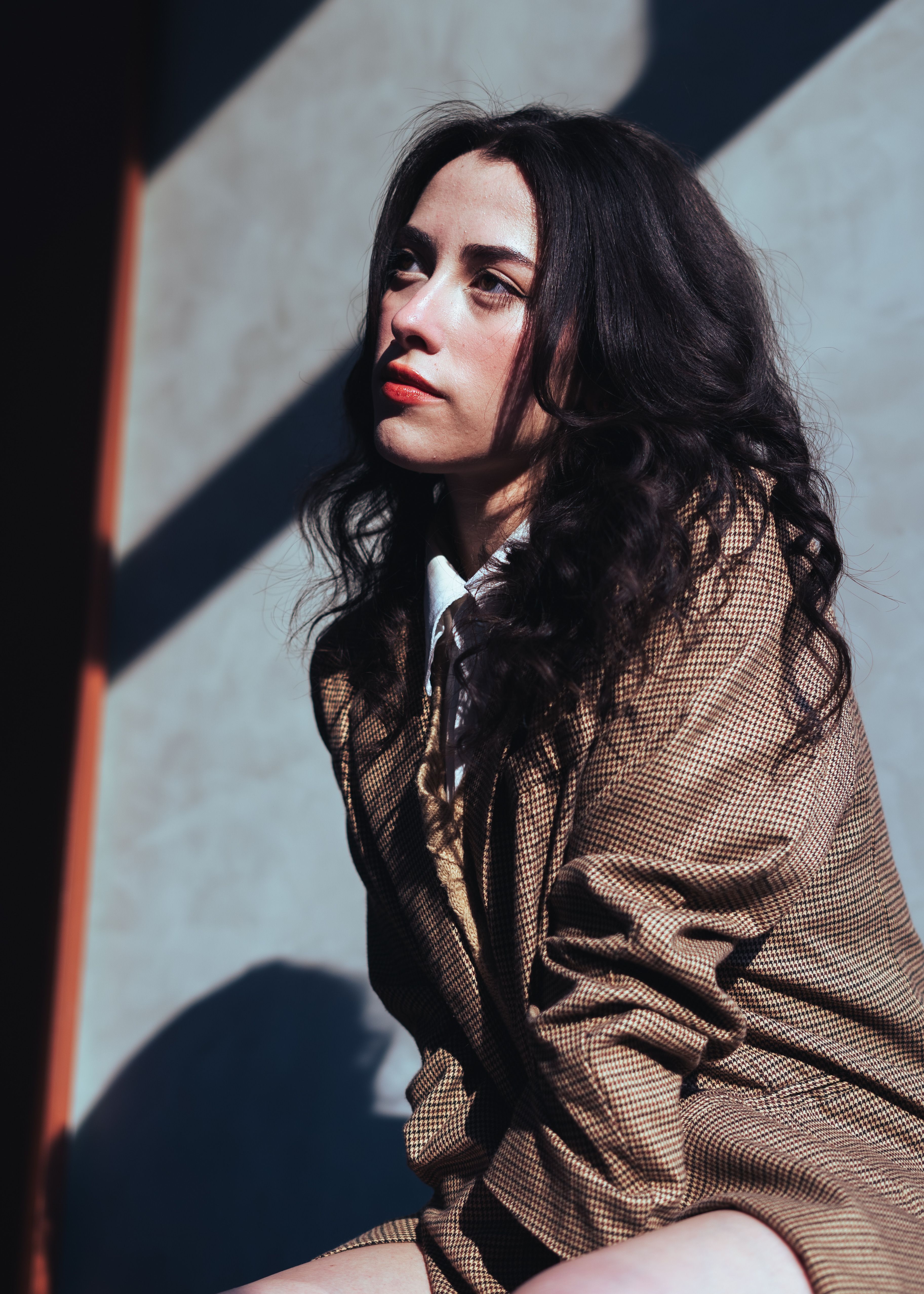 Stylish woman in vintage attire posed thoughtfully in indoor studio lighting.