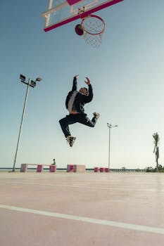 Man performing a dynamic jump on an outdoor basketball court at sunrise in Progreso, Mexico.