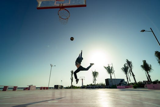Silhouette of a basketball player jumping for a dunk at sunrise in Progreso, Mexico.