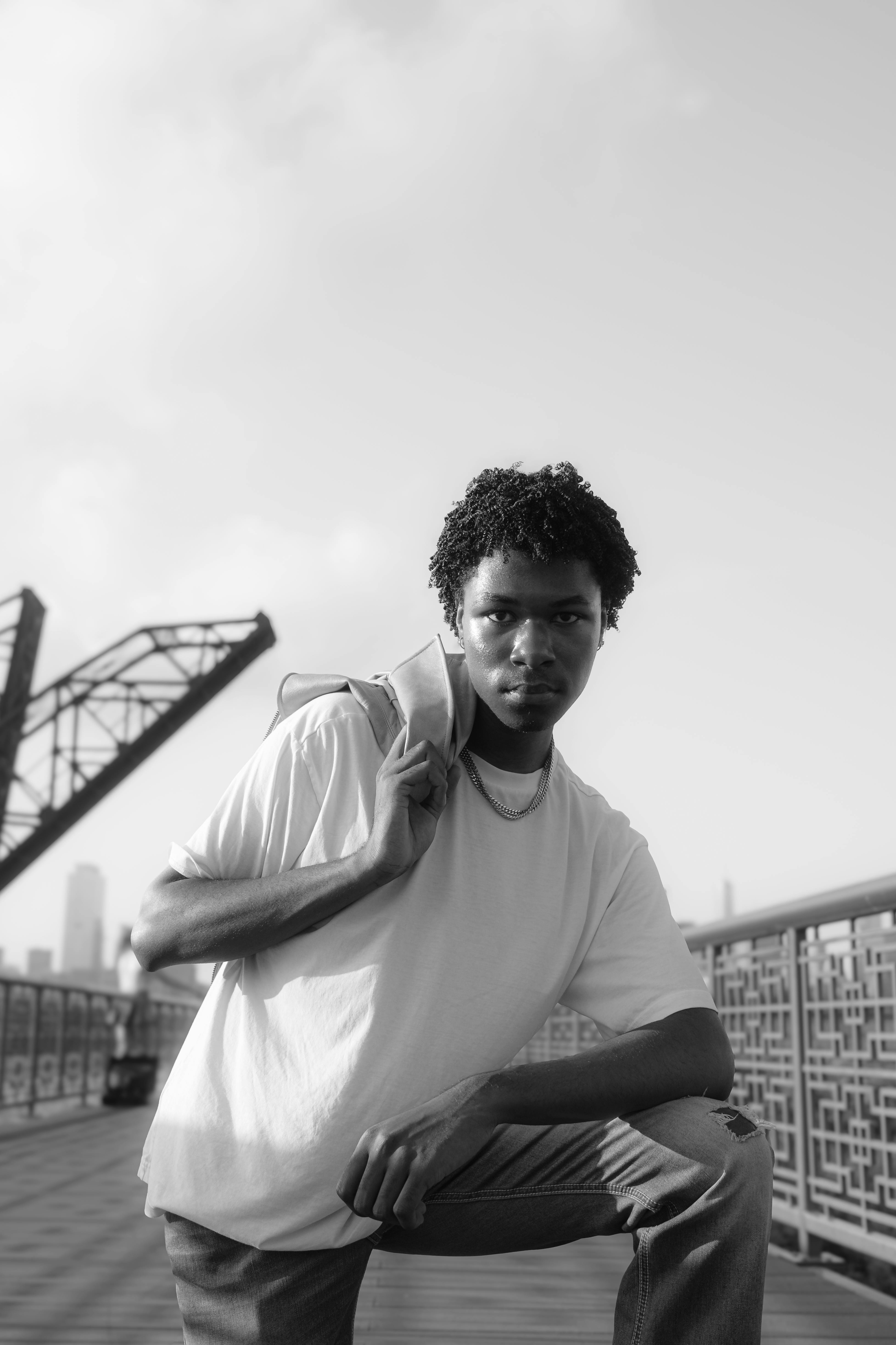 Black and white portrait of a young man on a bridge in Chicago, showcasing casual fashion.