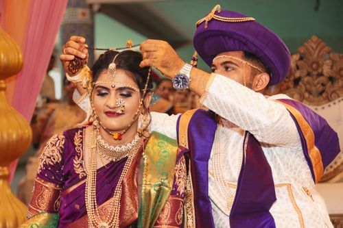 Free Bride and groom in traditional attire during an Indian wedding ceremony, exchanging jewelry. Stock Photo