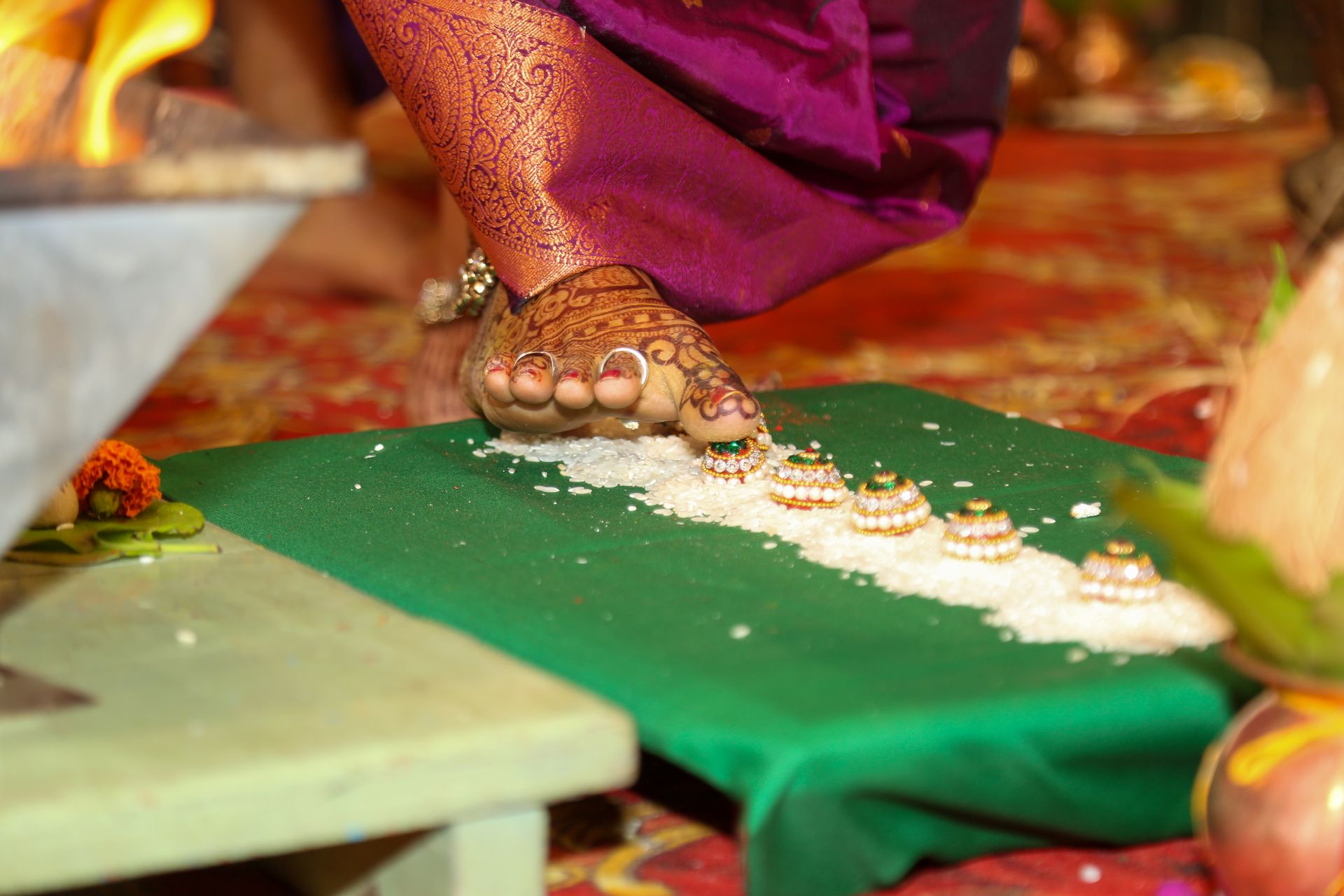 Close-up of a foot in a traditional Indian wedding ritual with henna and rice.