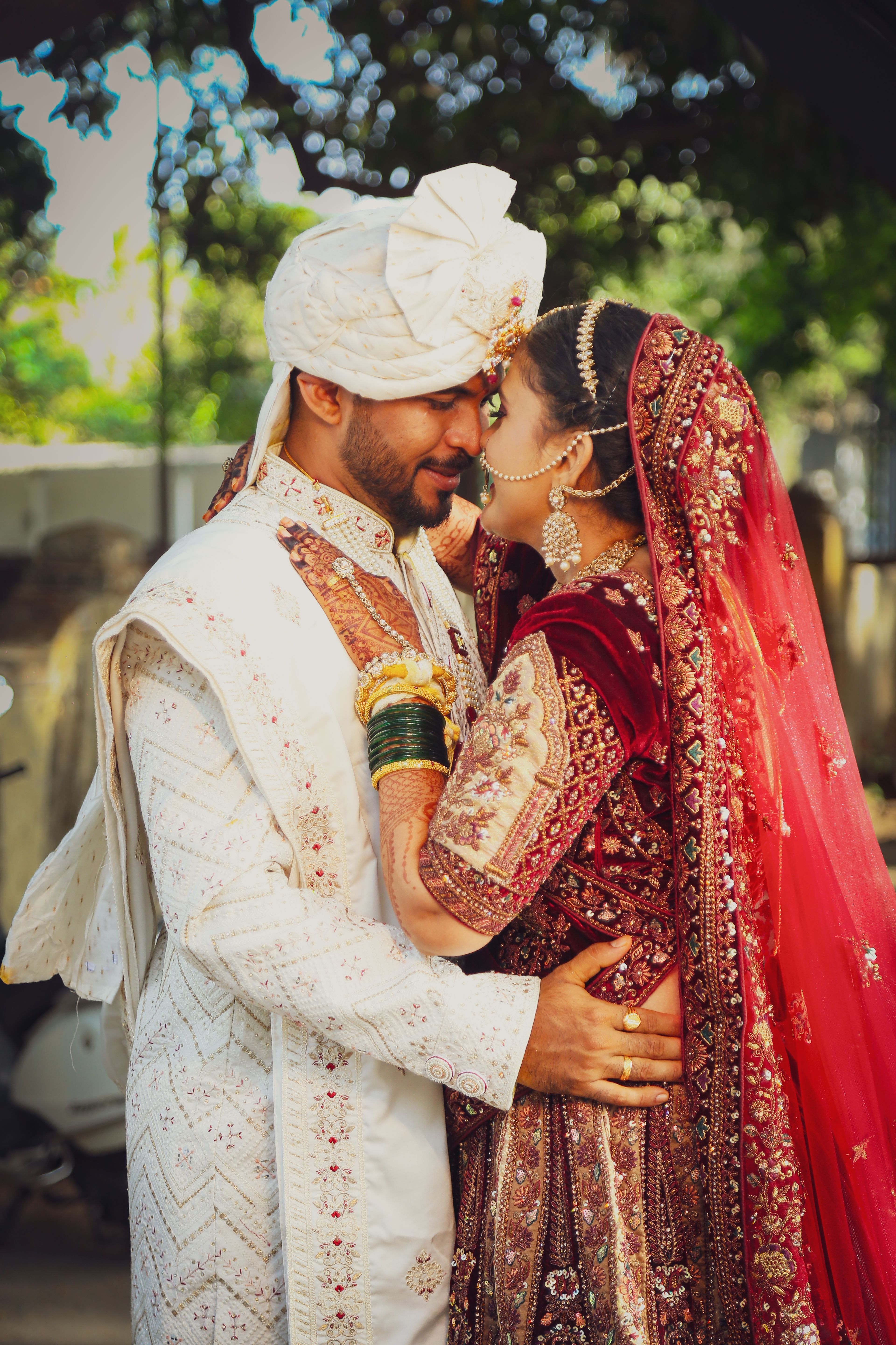 A bride and groom in traditional attire embracing outdoors, celebrating their wedding.