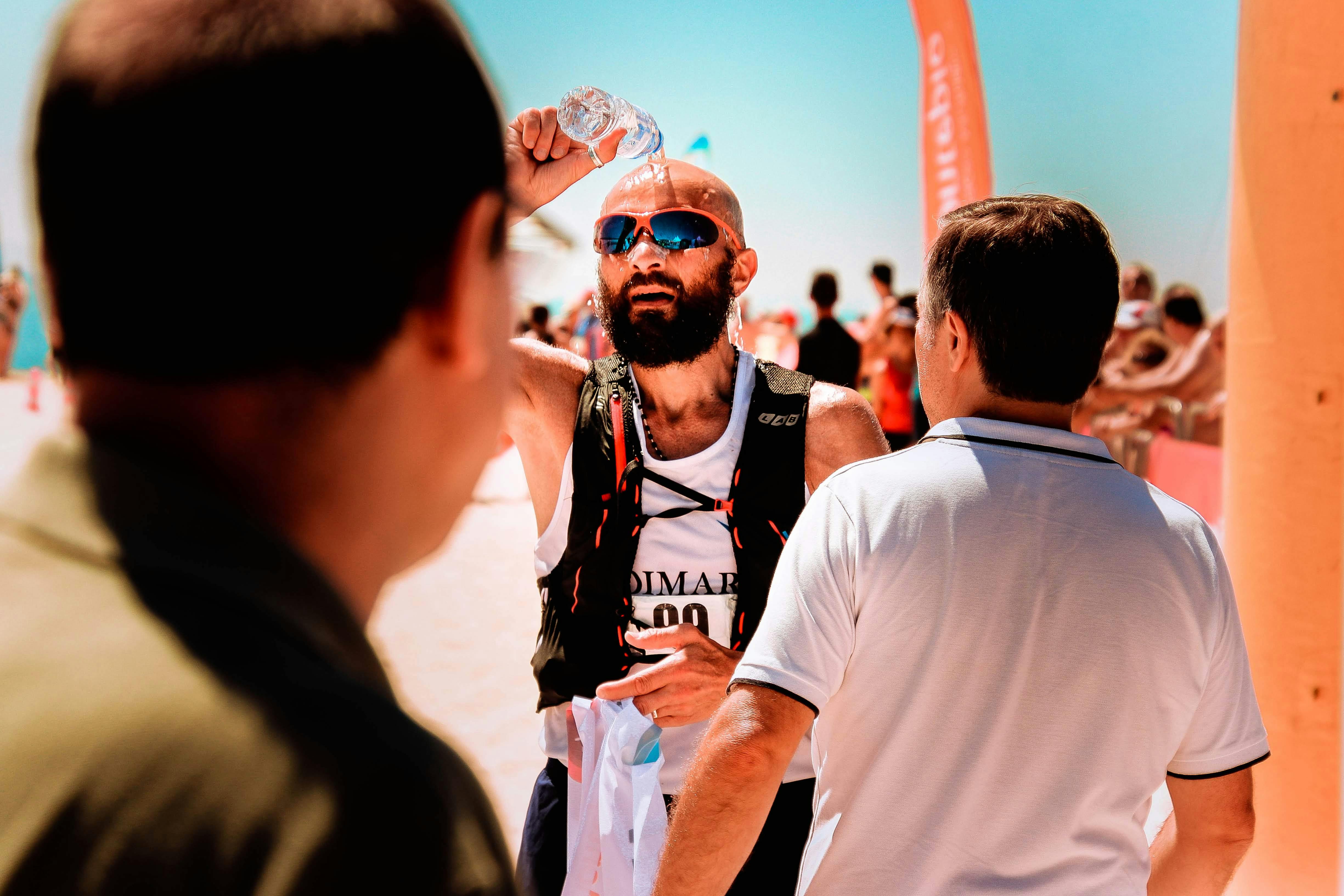 Corredor ech&aacute;ndose agua en la cabeza durante un punto de avituallamiento en una carrera