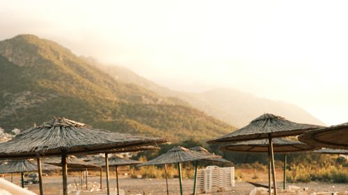 Free Tranquil beach scene with straw umbrellas and mountain view at sunset. Stock Photo