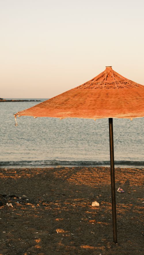 Free Tranquil scene of a beach umbrella on a sandy shore at sunset, perfect for relaxation and travel vibes. Stock Photo