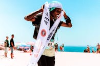 海滩马拉松比赛中，一名跑步者冲过终点线，赢得了胜利