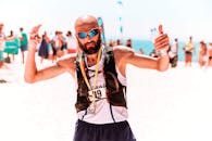 一名运动员在完成海滩马拉松后，戴着奖牌和太阳镜庆祝