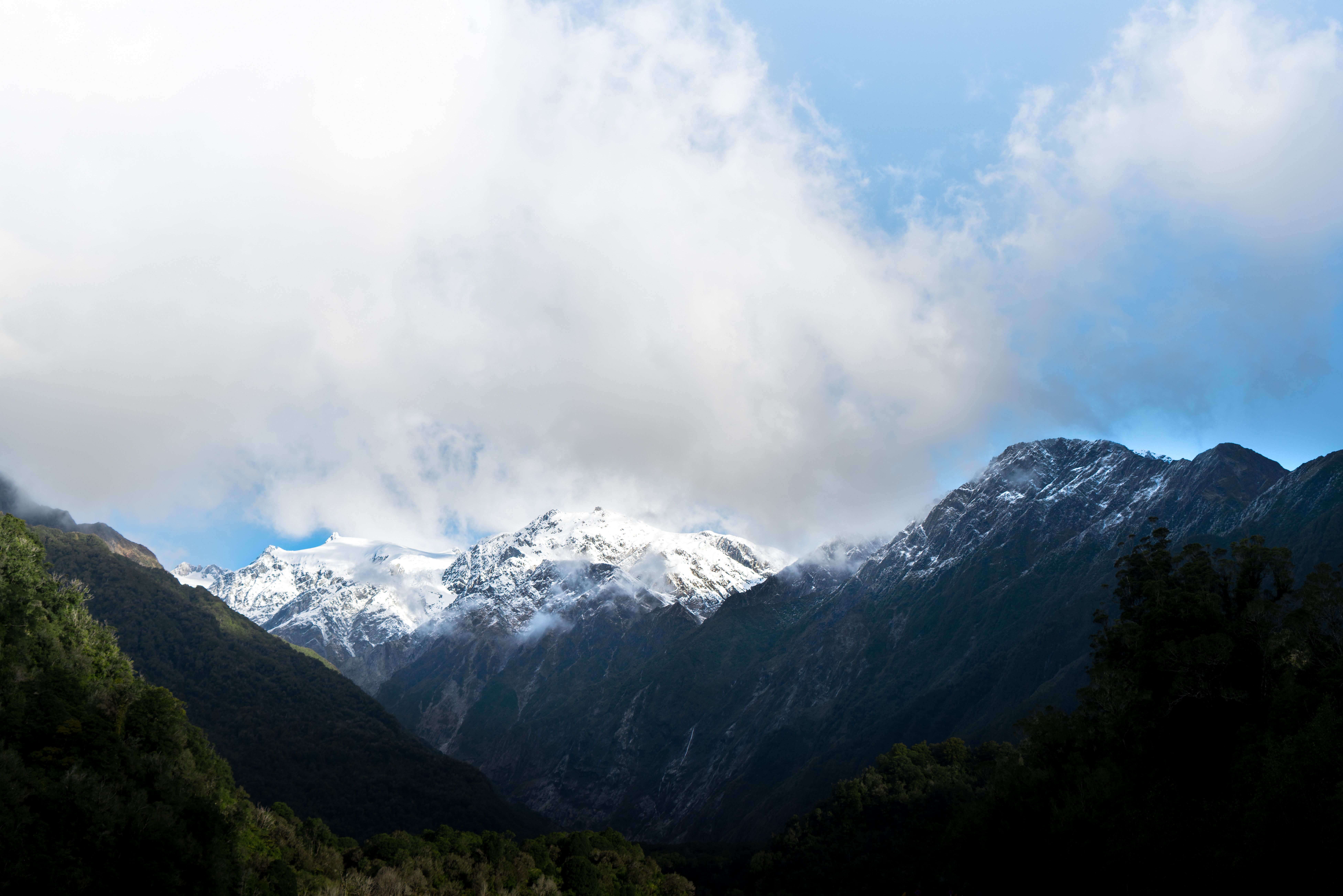 A mountain range with snow capped peaks and clouds · Free Stock Photo