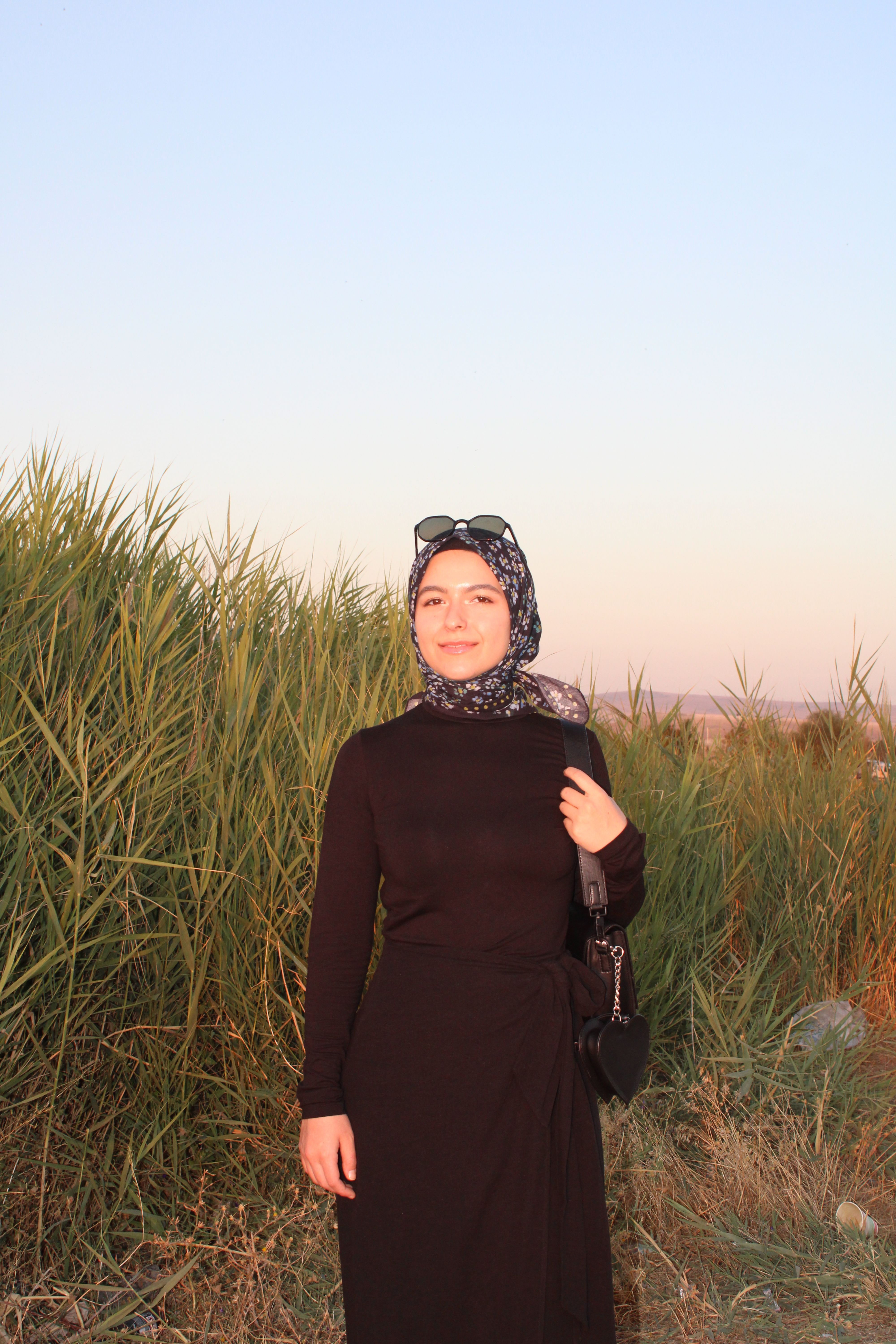 Portrait of a woman in hijab with a serene sunset backdrop, conveying calmness and style.