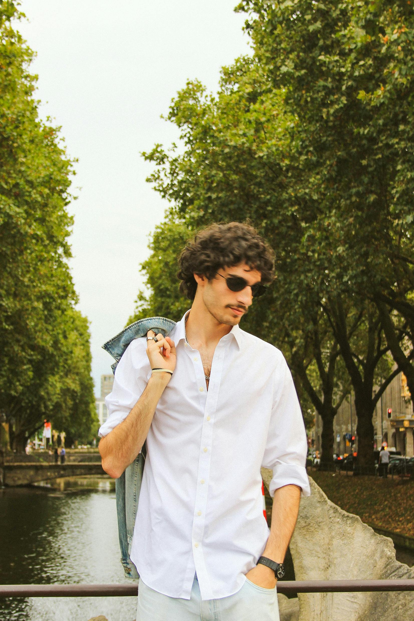 A fashionable man in sunglasses enjoys a leisurely walk along the Königsallee canal in Düsseldorf, Germany.