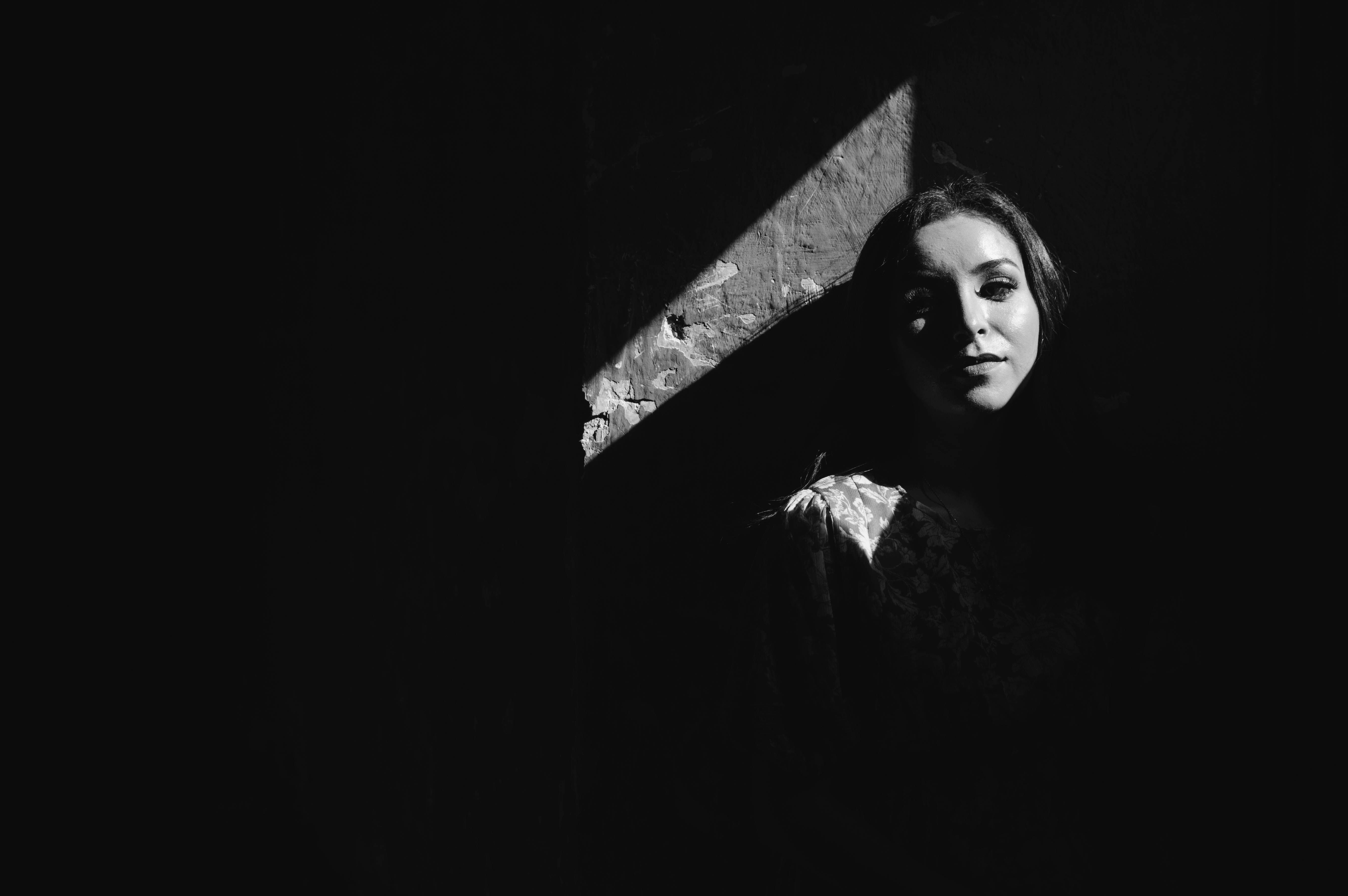 A woman in black and white is standing in the shadows · Free Stock Photo