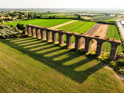 Free Aerial view of a historic aqueduct in lush Antalya farmland, casting shadows on the crops. Stock Photo
