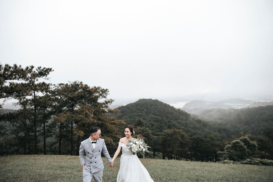 Bride and groom walking hand-in-hand in a scenic rural setting.