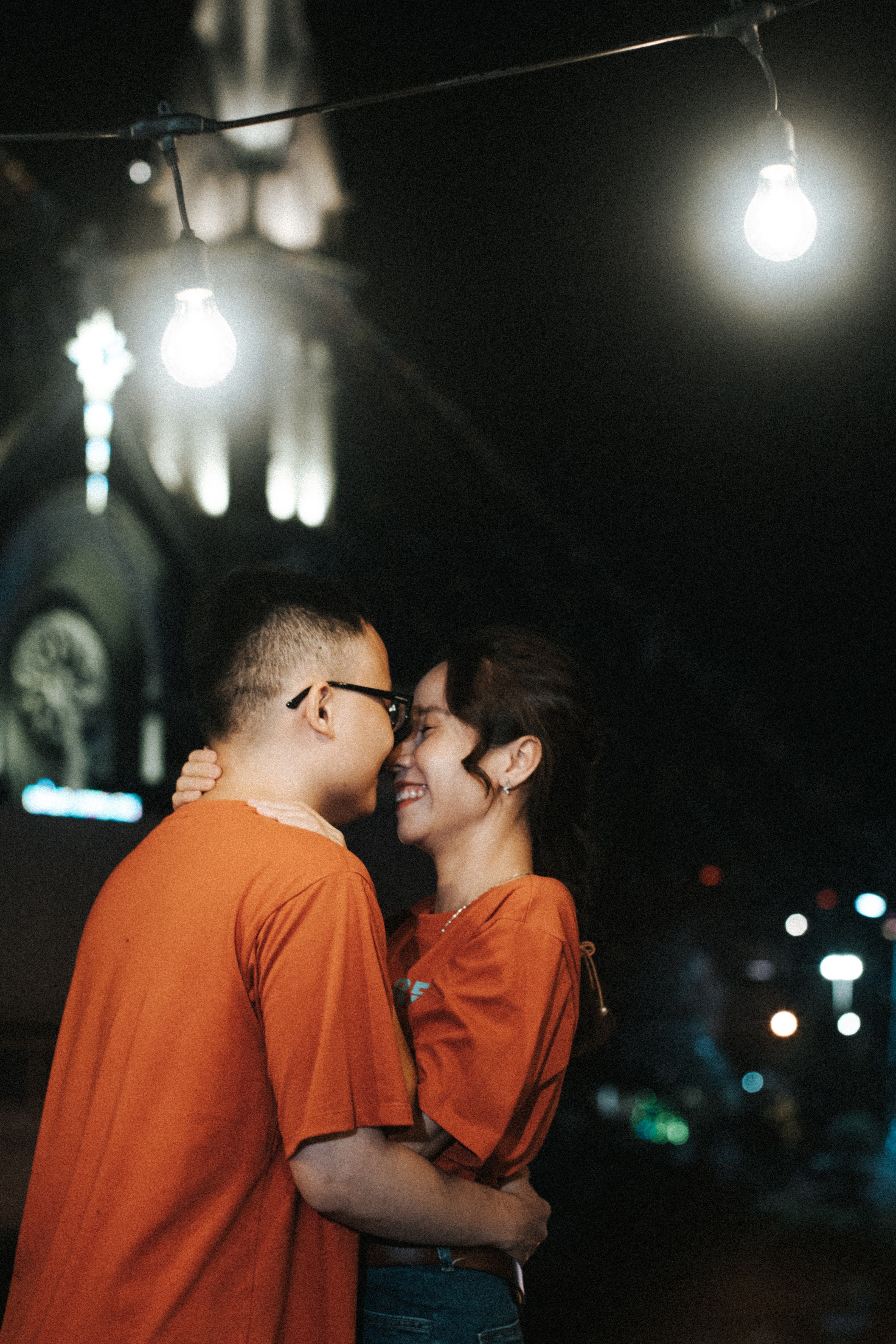 Free A loving couple shares a tender moment under streetlights at an outdoor festival. Stock Photo