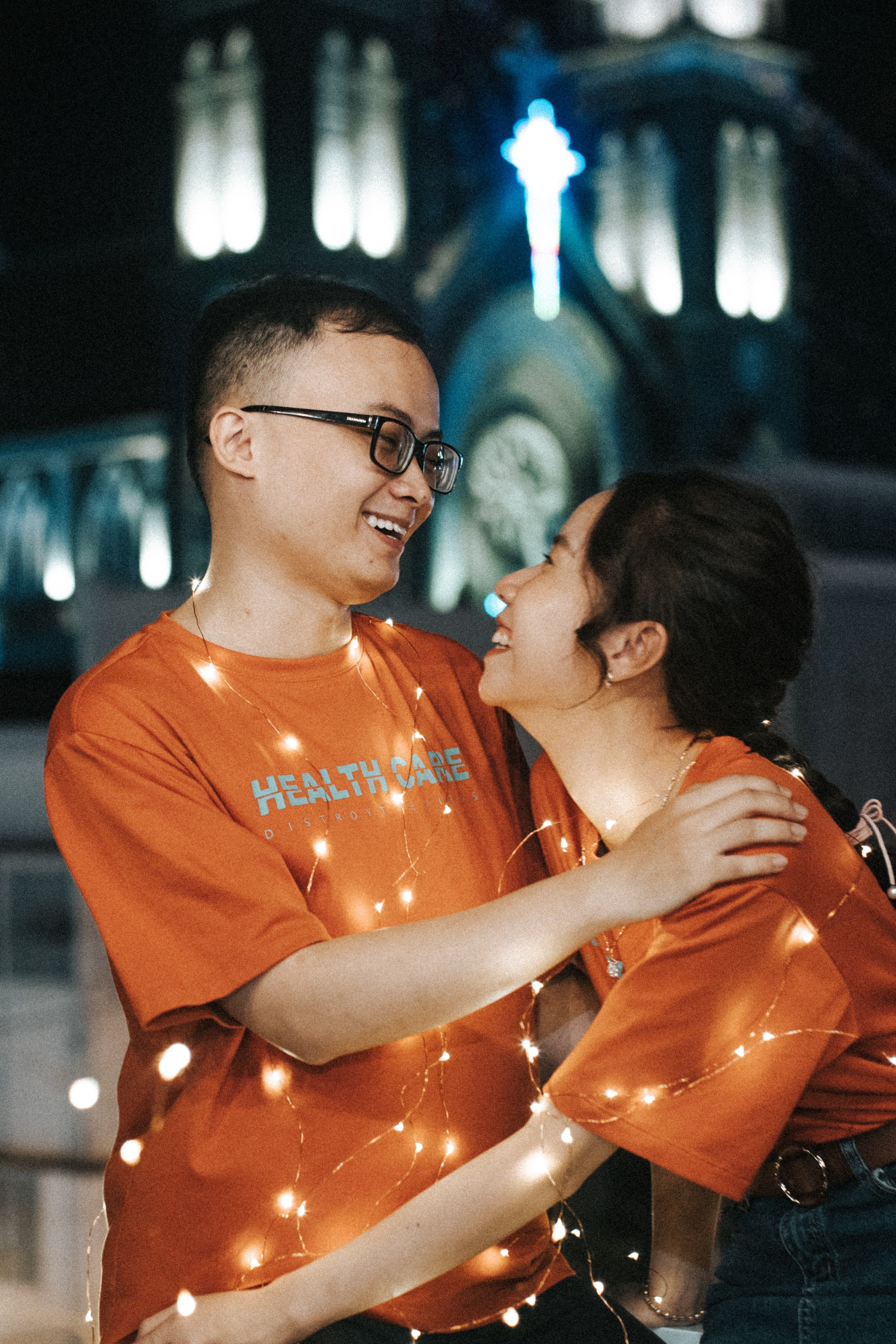 Free A joyful couple embracing at night, adorned with warm string lights, exuding romance and happiness. Stock Photo