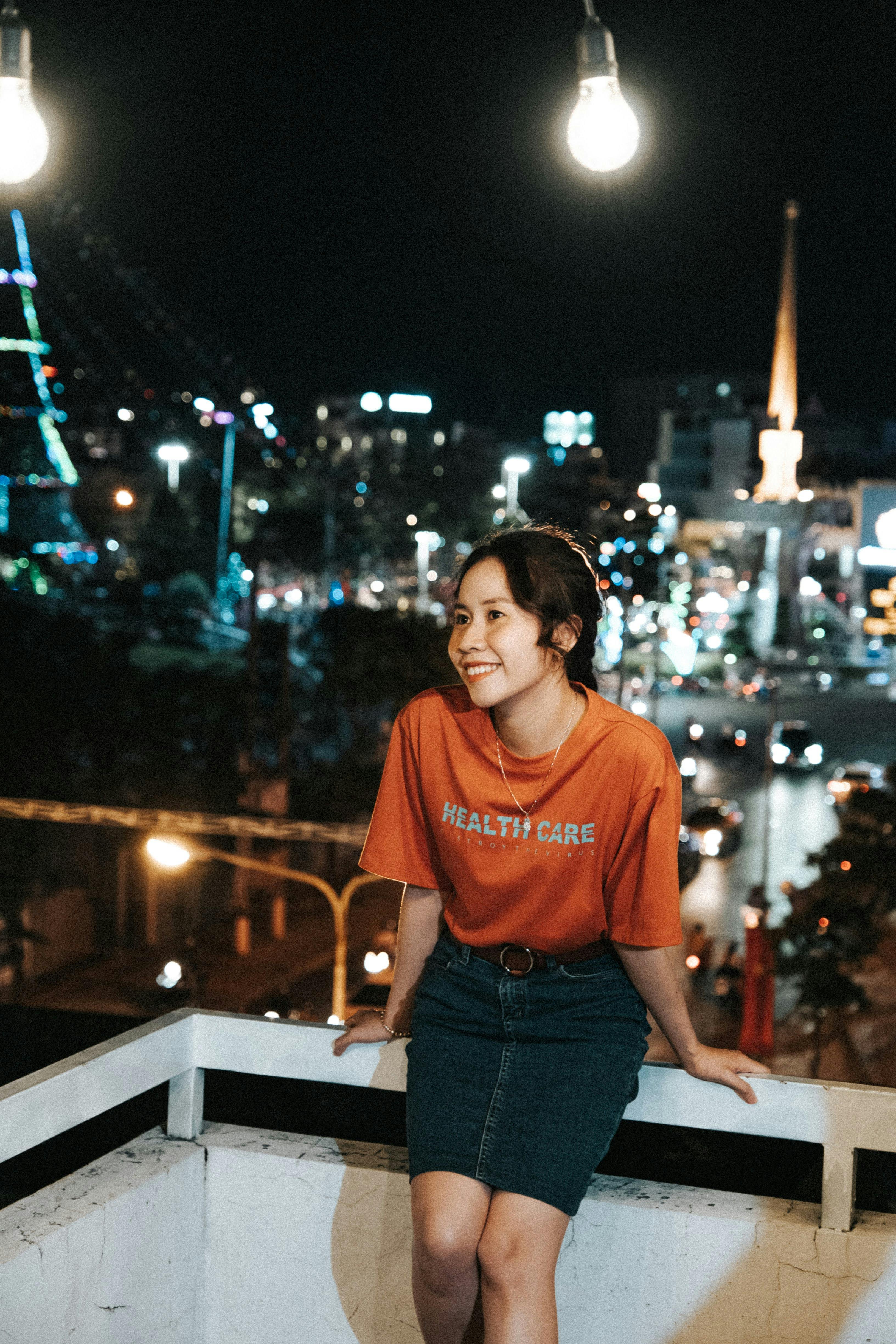 a woman in an orange shirt and skirt standing on a balcony