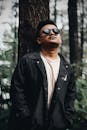 一名戴着太阳镜、穿着夹克的男子在森林中自信地摆姿势