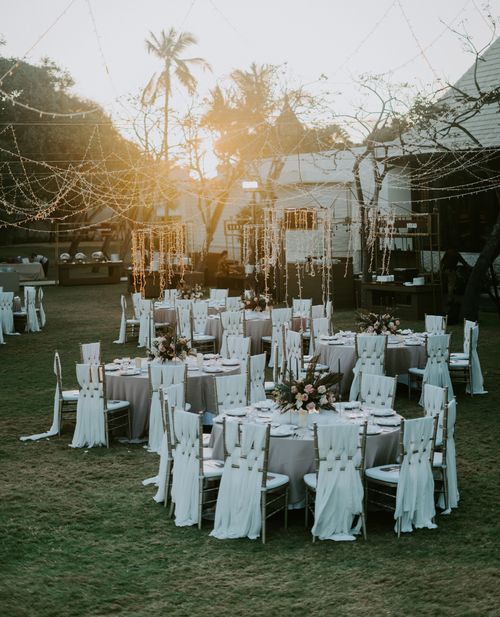 Free Charming sunset-lit outdoor wedding setup with adorned tables and chairs, perfect for celebrating love. Stock Photo