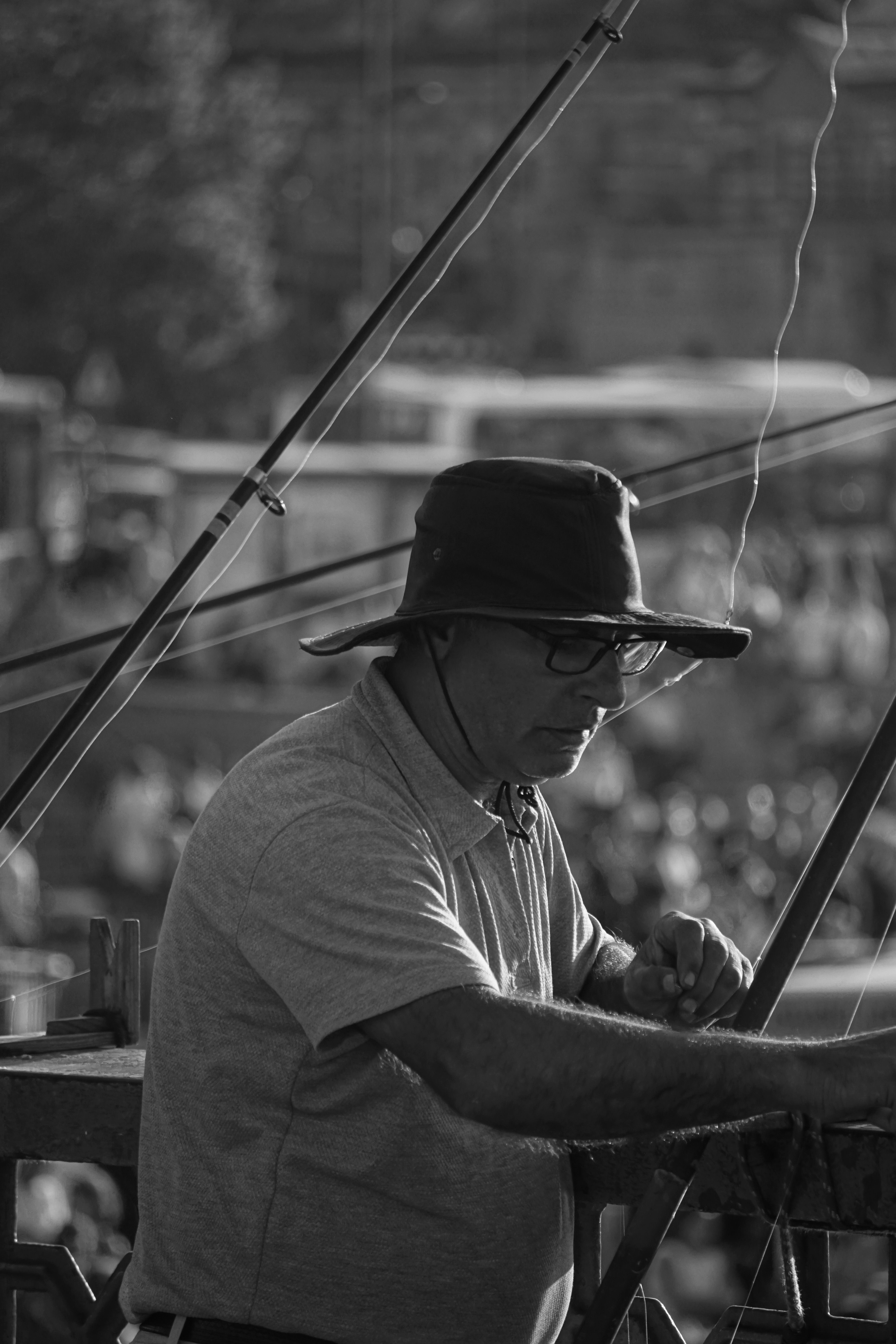A contemplative black and white image of a fisherman on a pier, surrounded by fishing gear.