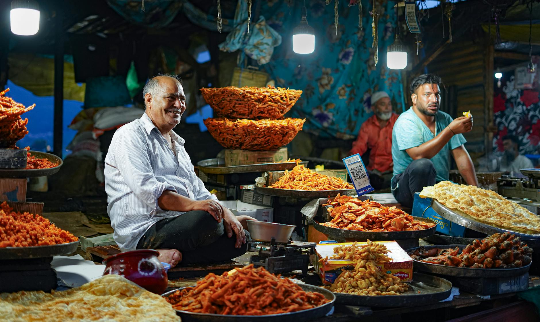 Lively street market in Srinagar, India showcasing local vendors selling traditional snacks under bright lights.