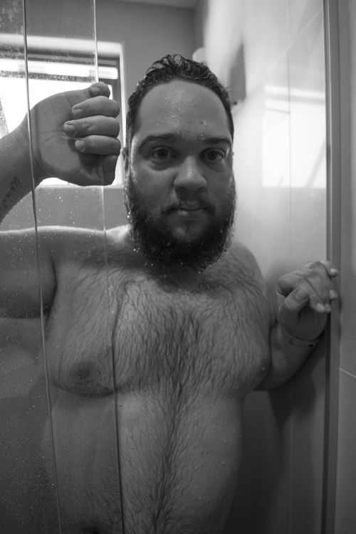 Free A bearded man stands confidently in the shower, captured in a black and white portrait. Stock Photo