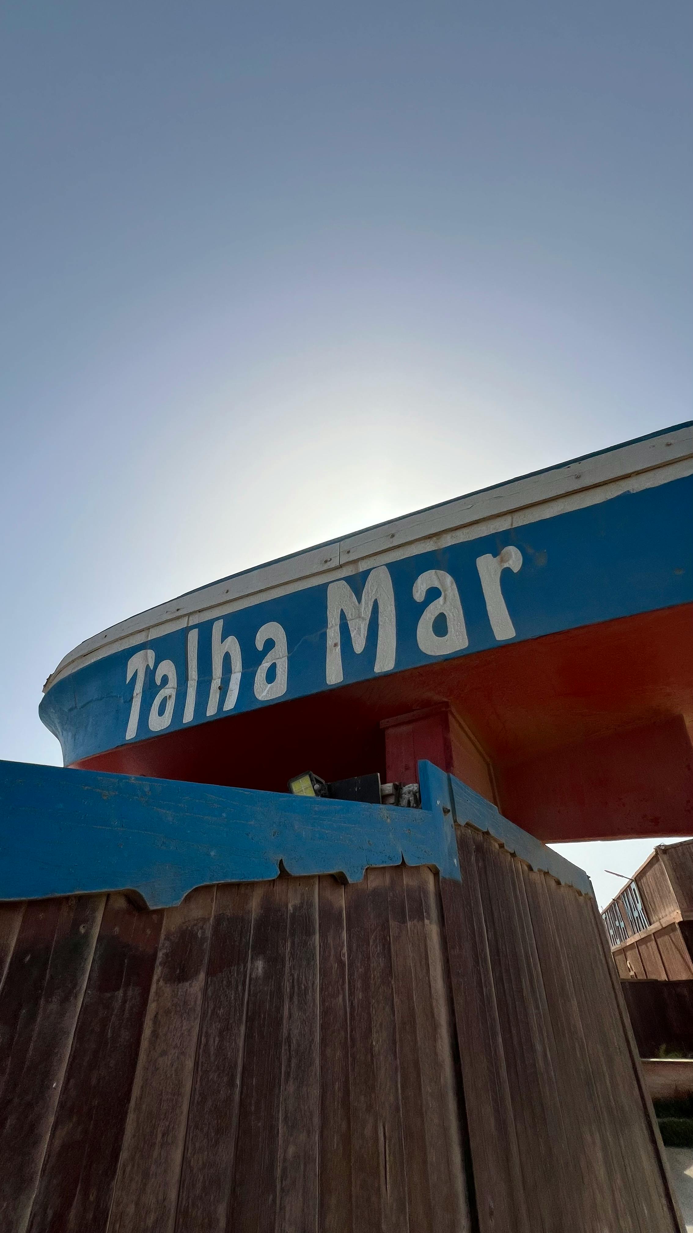 Close-up of a vibrant boat with 'Talha Mar' text, framed by a clear blue sky.