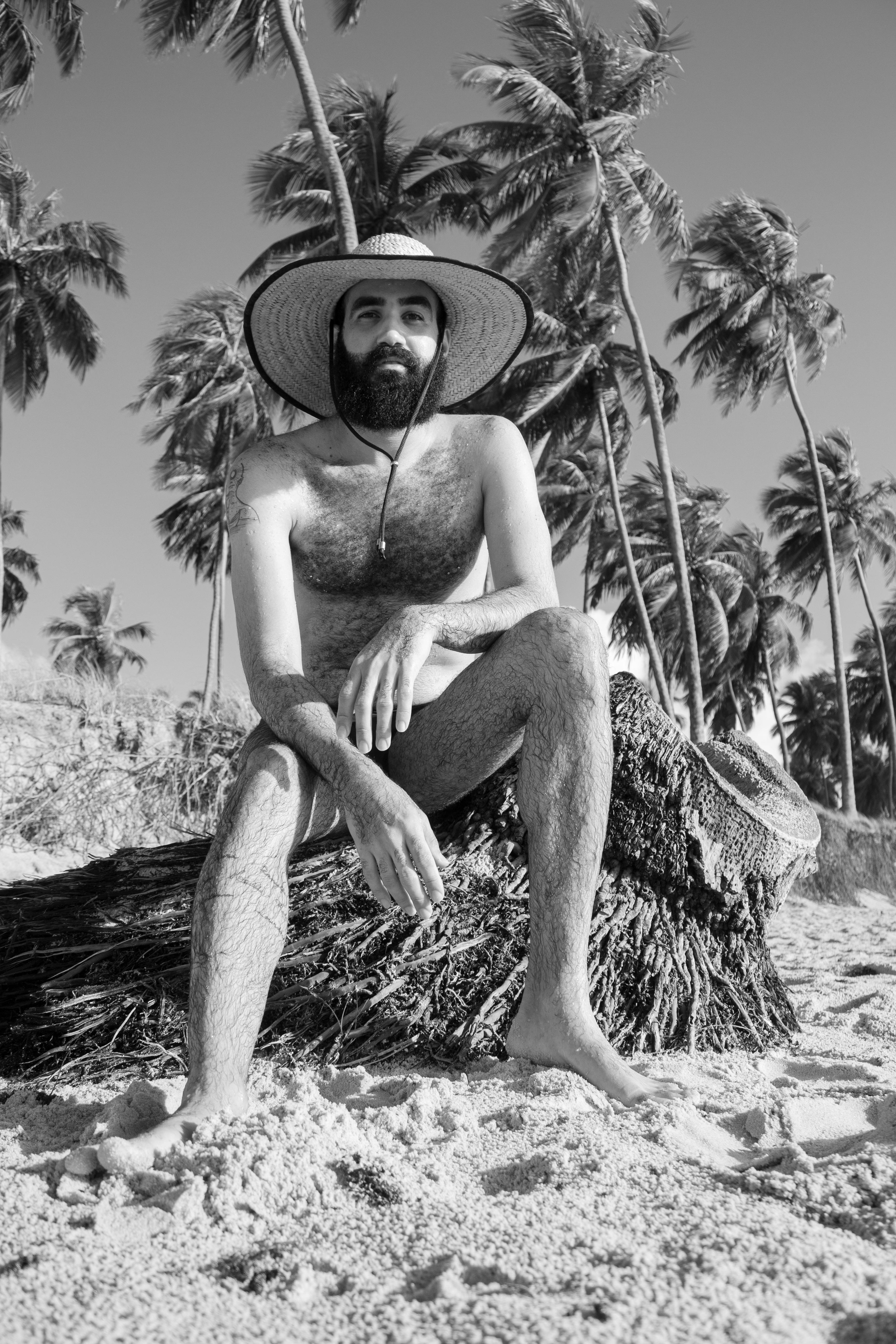 a man with a hat and a straw hat sitting on a beach