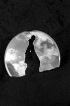 Silhouette of a person reflected in a mirror against a cloudy sky.
