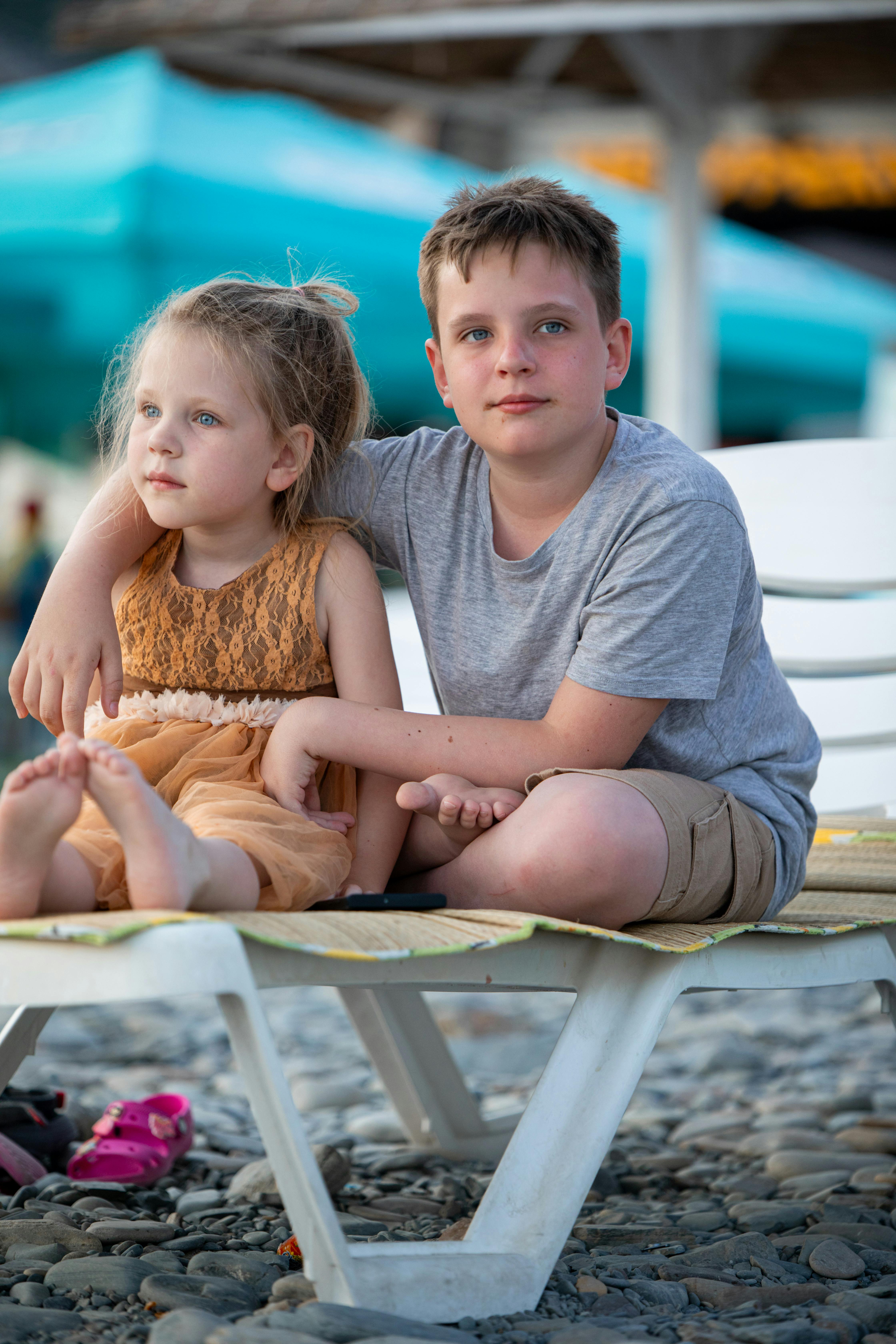 a boy and girl sitting on a beach chair