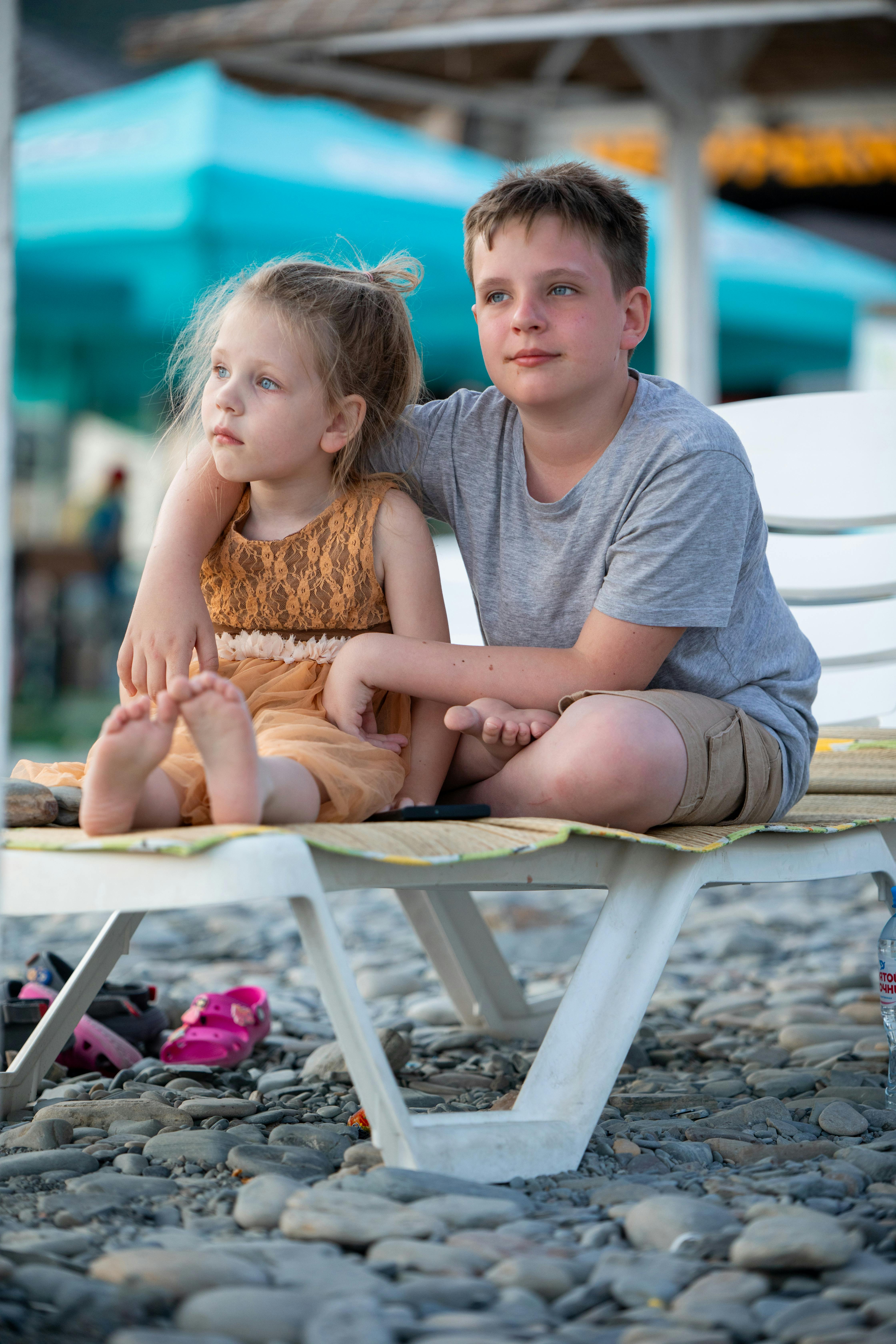 a boy and girl sitting on a beach chair