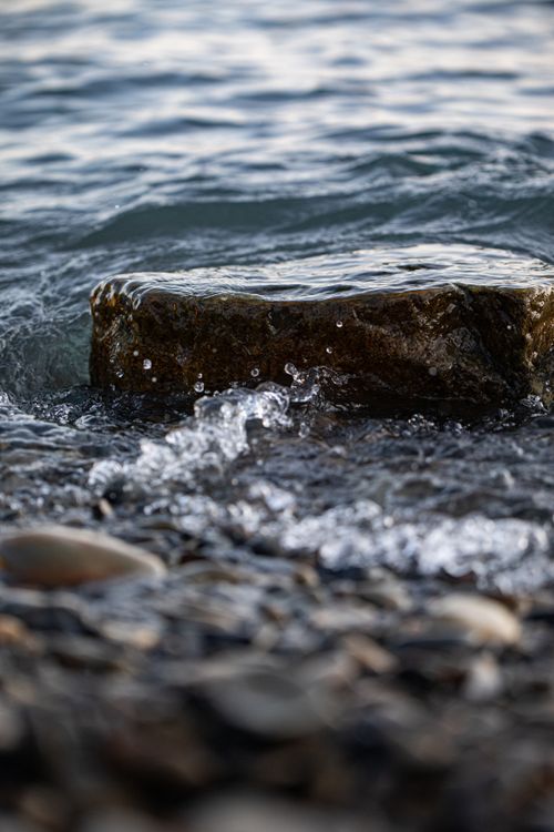 Free Peaceful seascape with gentle waves hitting rocks on a serene beach shore. Stock Photo