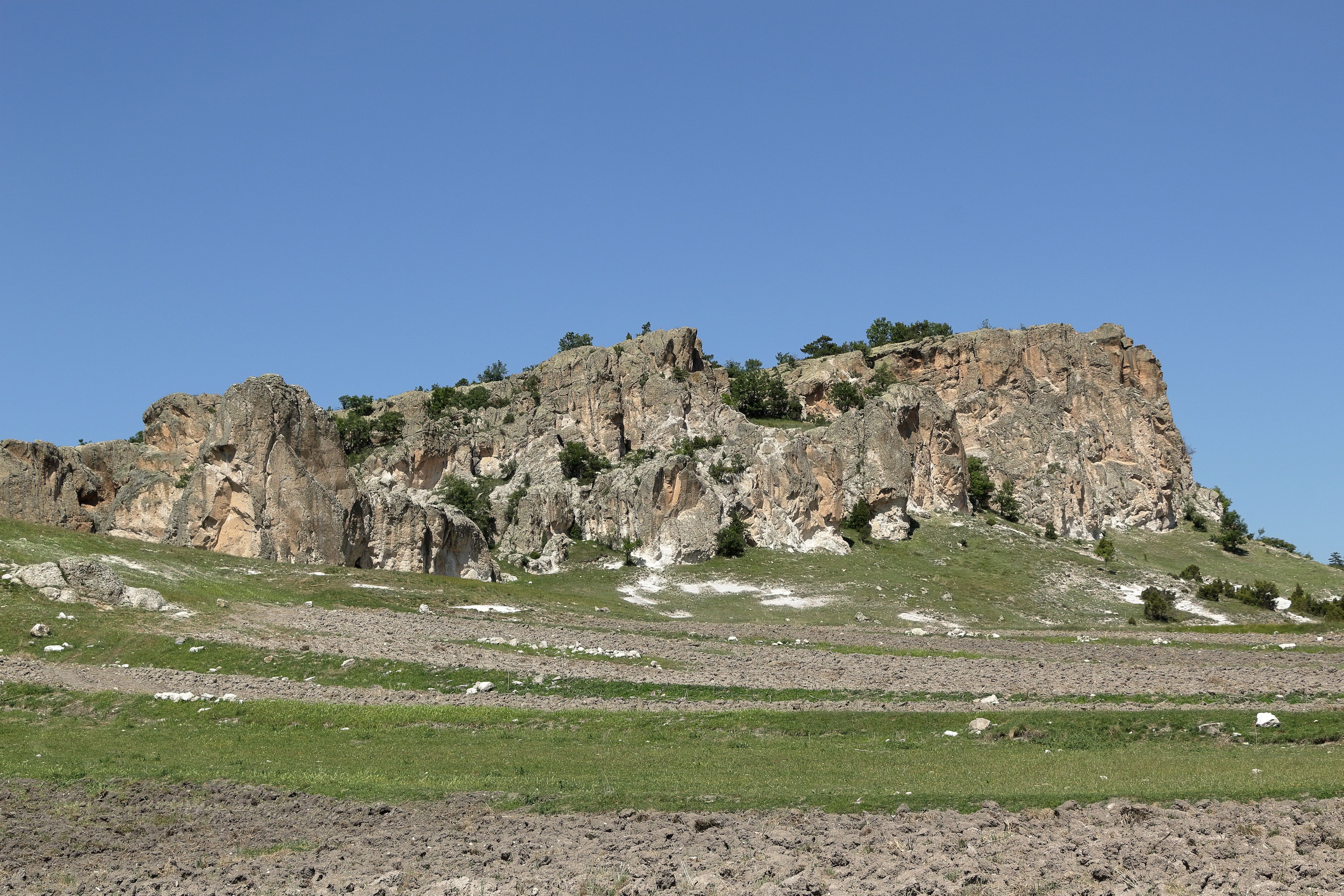 A large rock formation in the middle of a field · Free Stock Photo