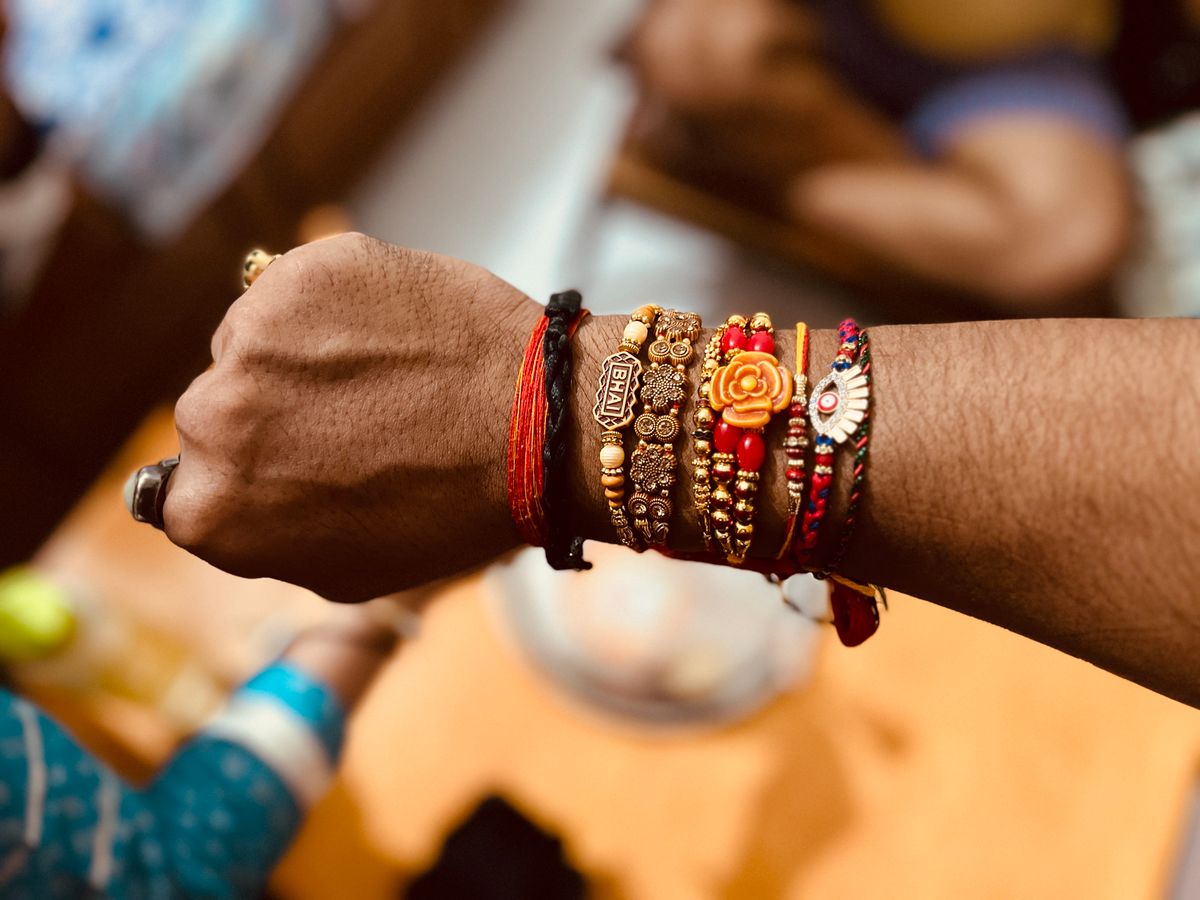 A wrist stacked with colourful rakhi threads and bracelets