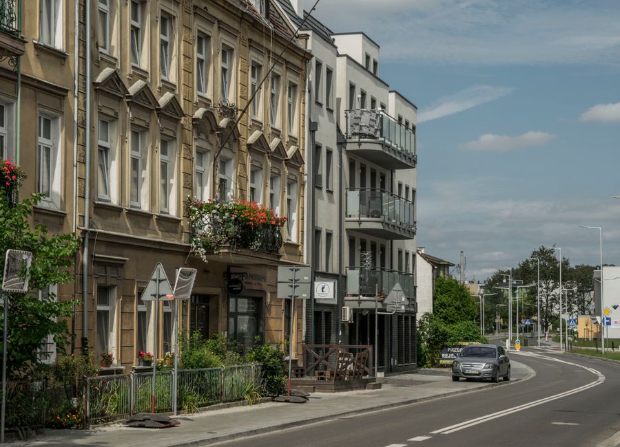 Street view of residential buildings and a car in Wrocław, showcasing city life.