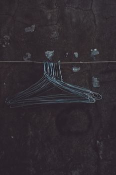 Cluster of wire hangers suspended against a dark, textured background, creating an abstract vibe.