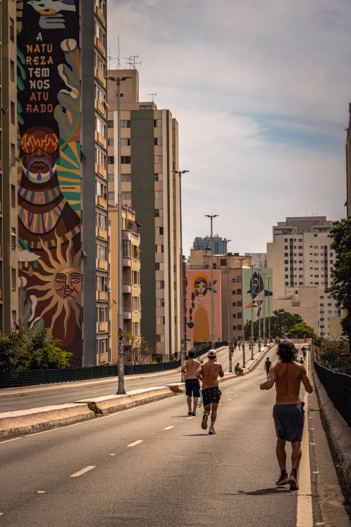 Free Vibrant street art with people running in São Paulo's urban landscape at sunset. Stock Photo