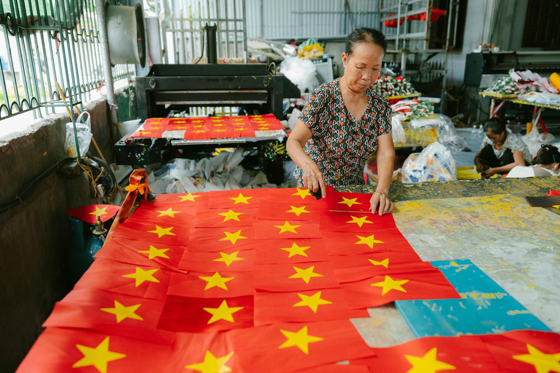 A woman is working on a large flag with stars