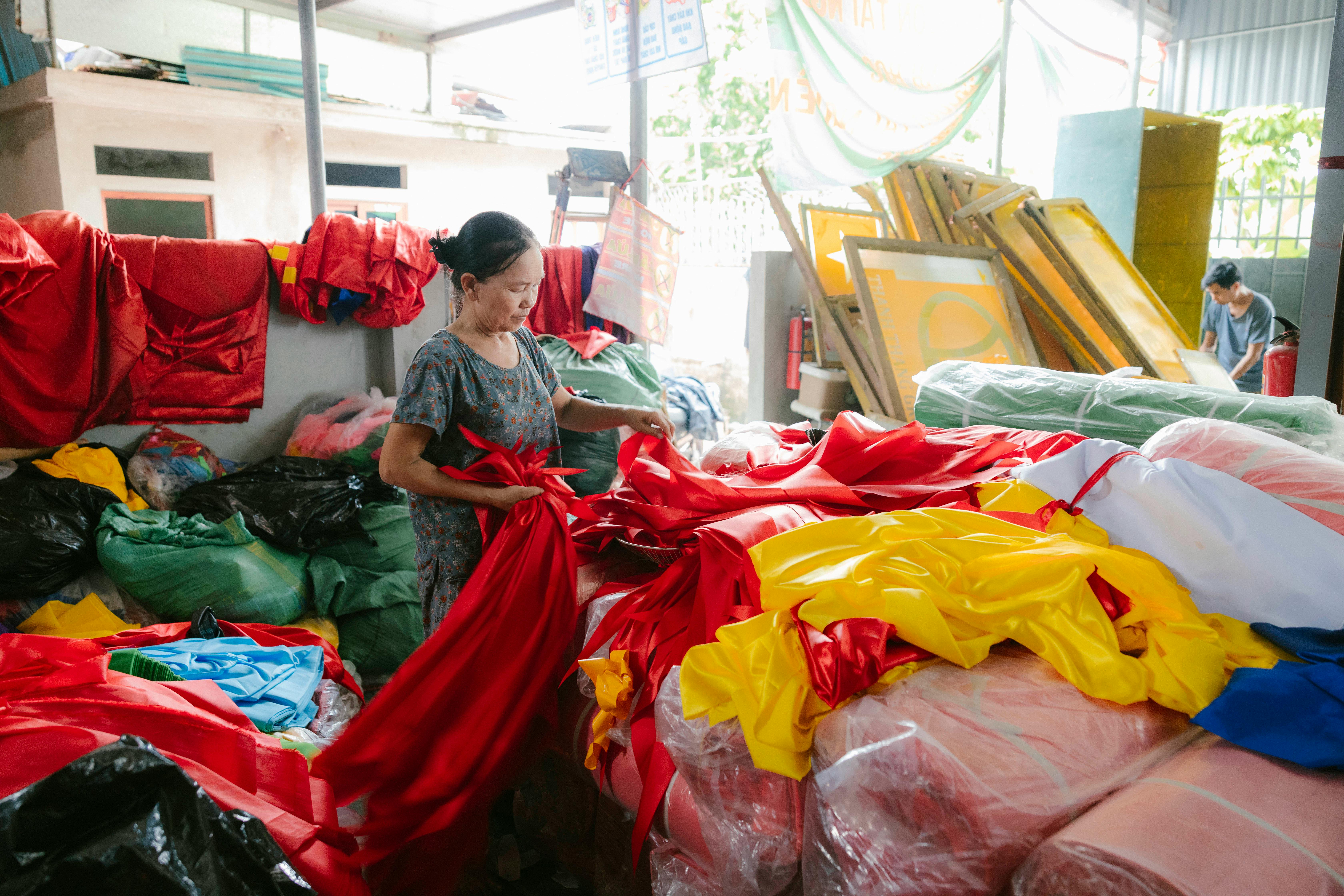 a woman is sorting out the fabric in a warehouse