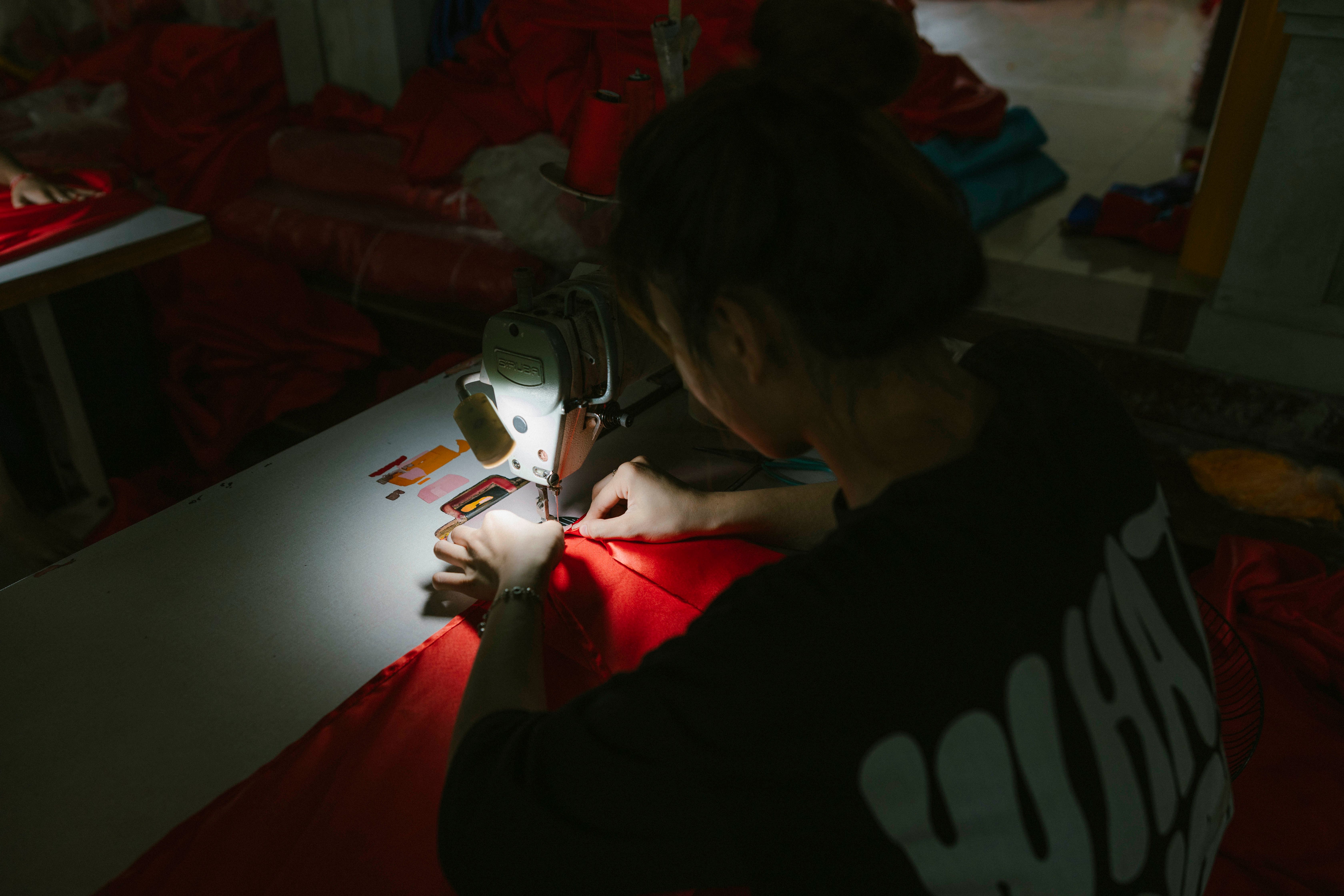 A young woman skillfully operating a sewing machine, highlighting manual craftsmanship.