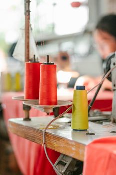 Red and yellow spools on a sewing machine highlight creativity in a bustling workshop.