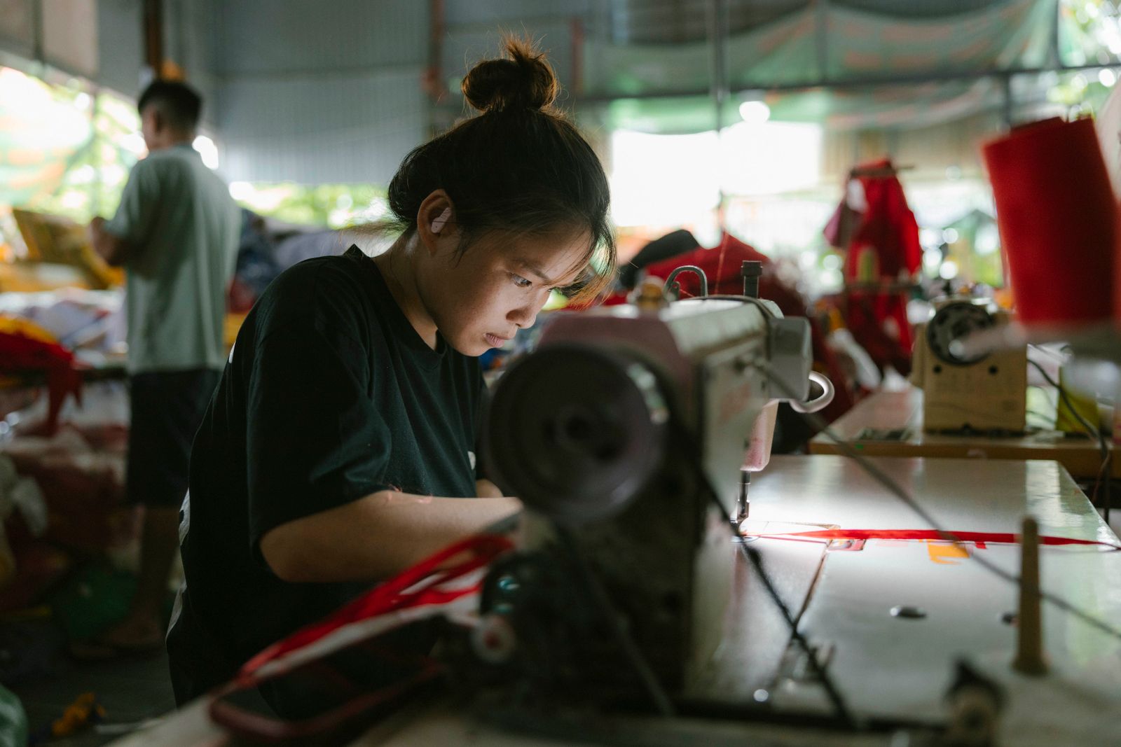 A machinist sewing at an industrial machine in a busy workshop