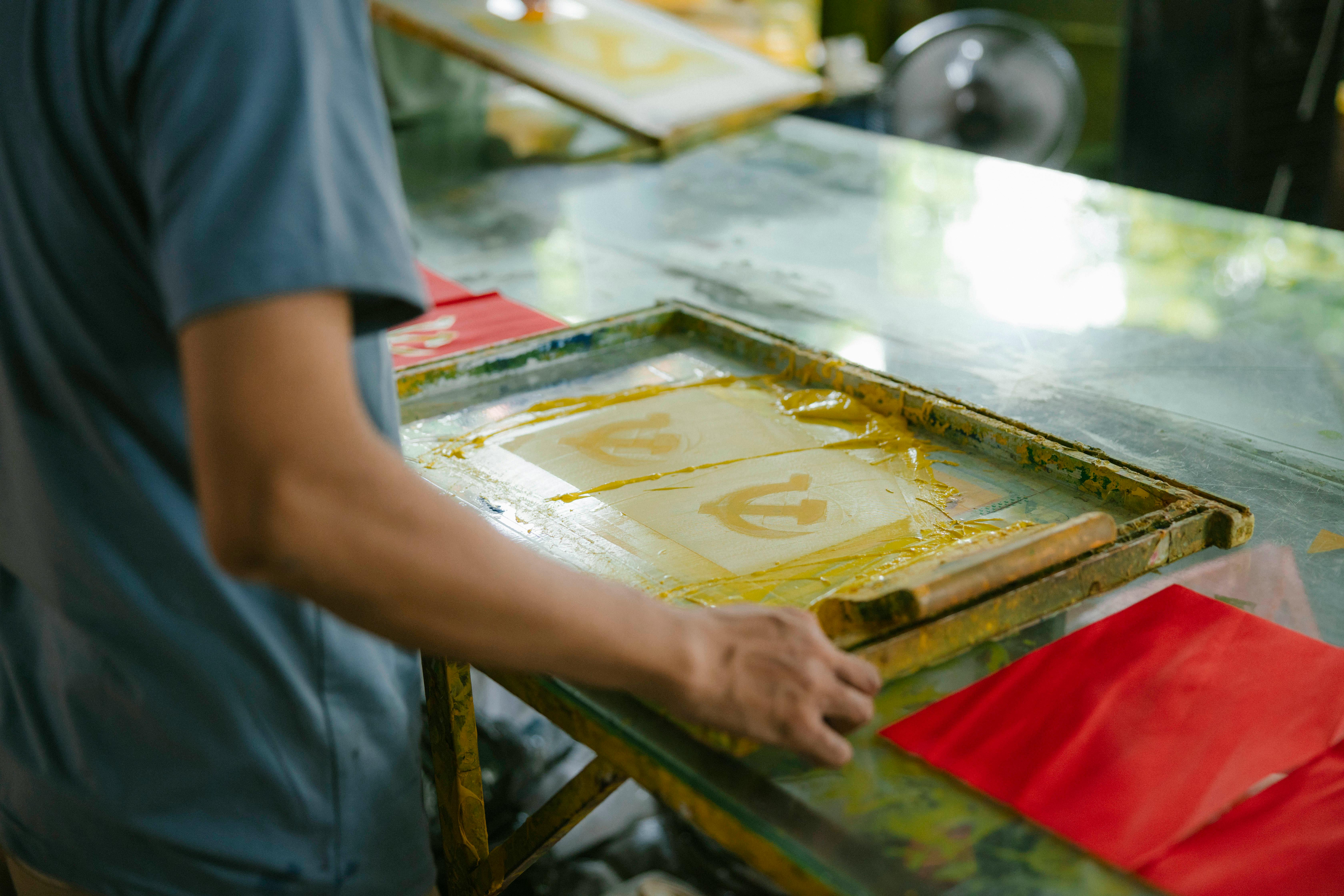 a man is working on a screen printing machine