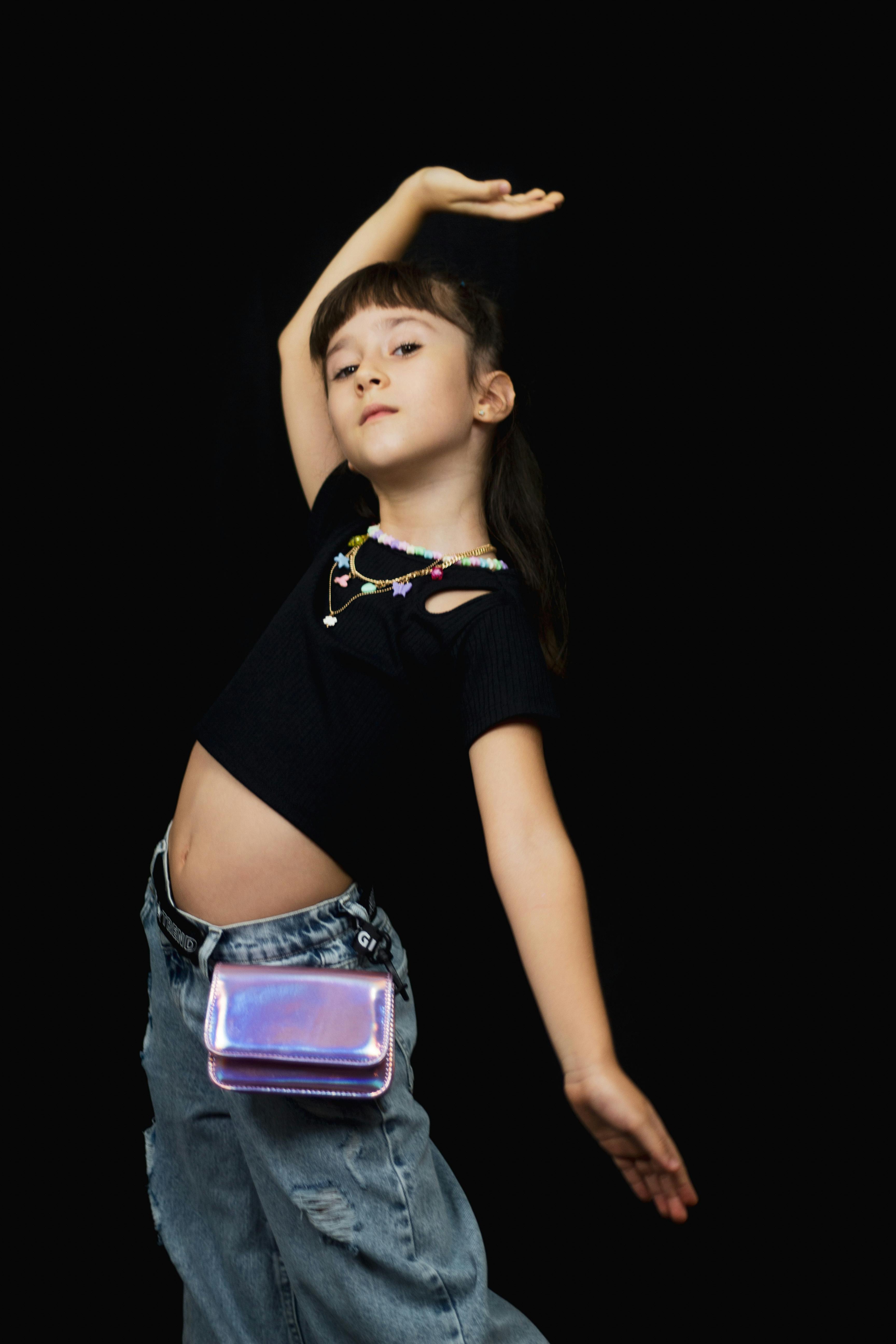 a young girl in a black top and jeans is dancing