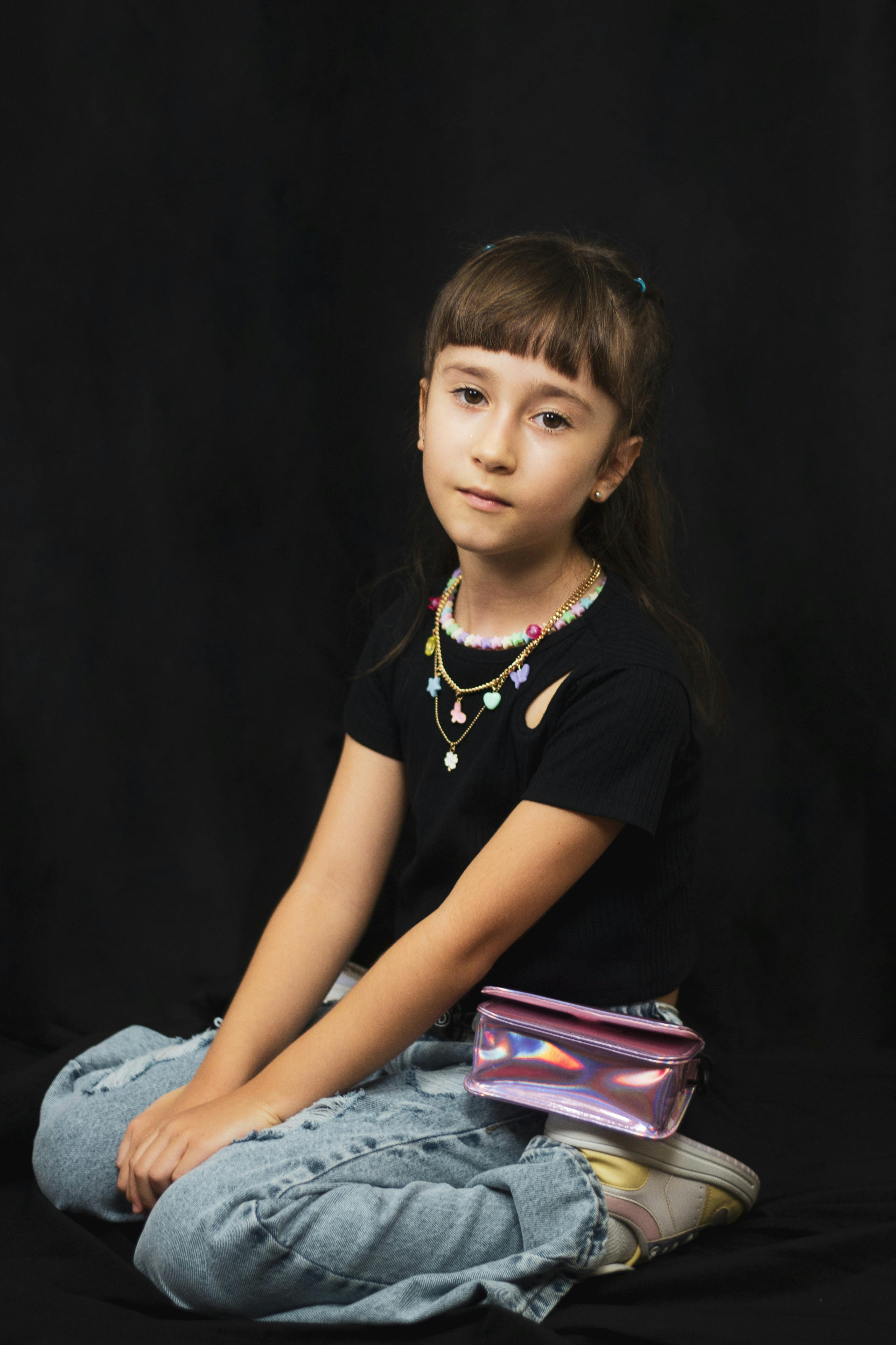 a little girl sitting on the floor with a purse